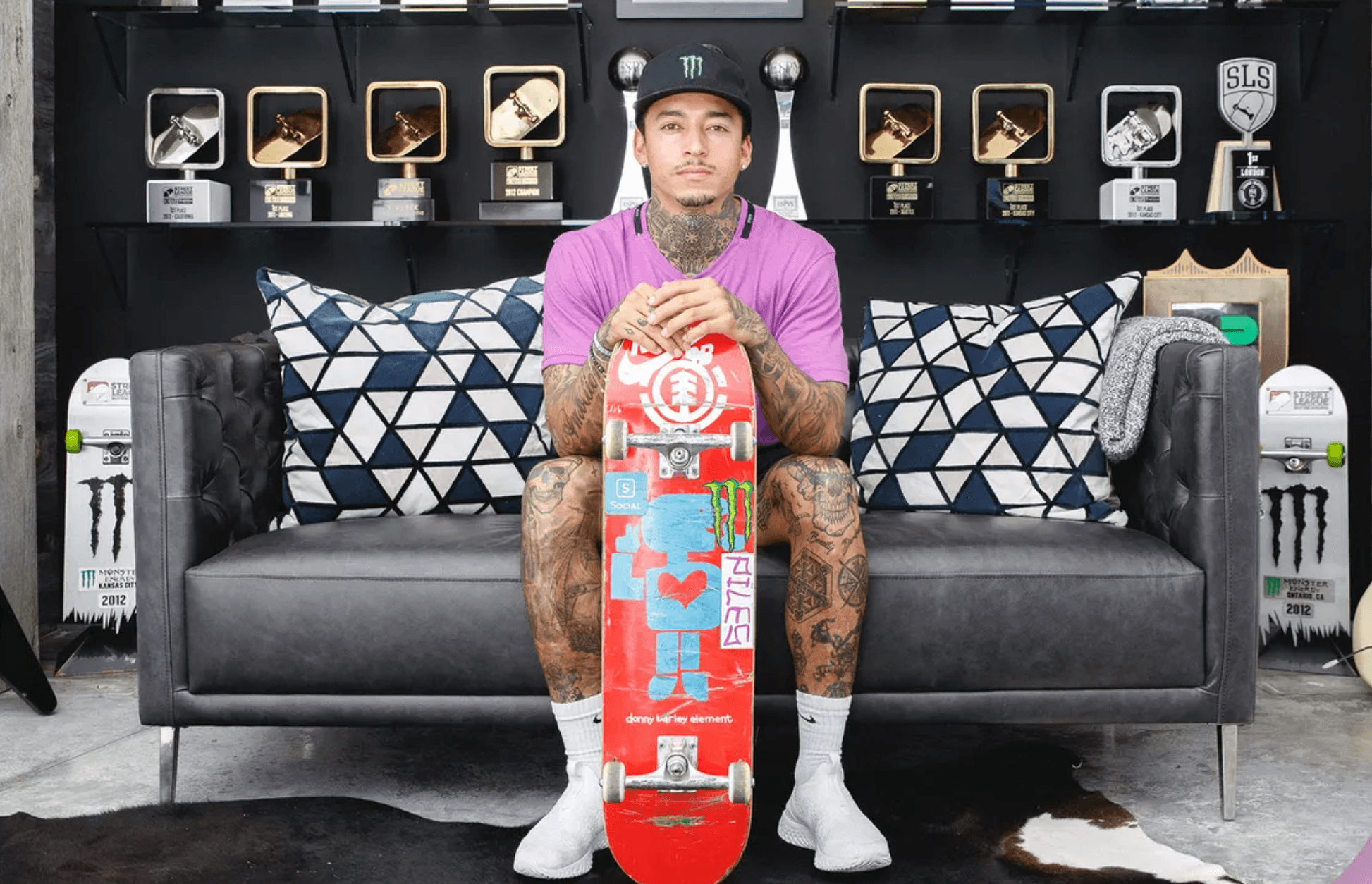 skateboard Nyjah Huston holding skateboard sitting on gray couch