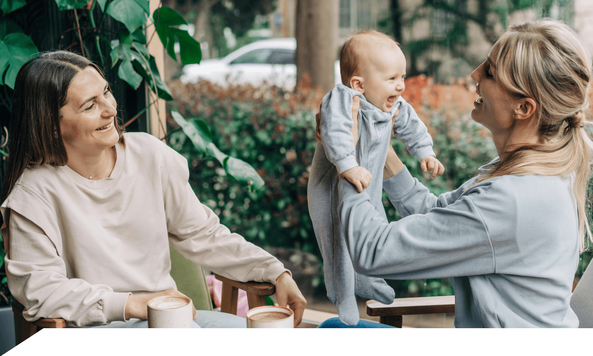 Two women sitting outside, one holding a baby