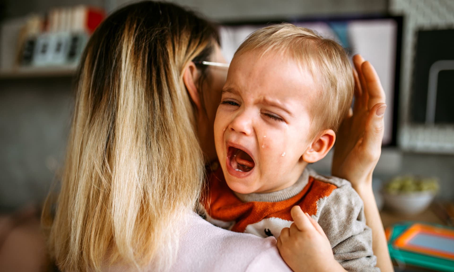 mom holding her crying toddler