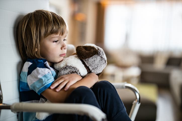 child with stuffed dog sitting on chair