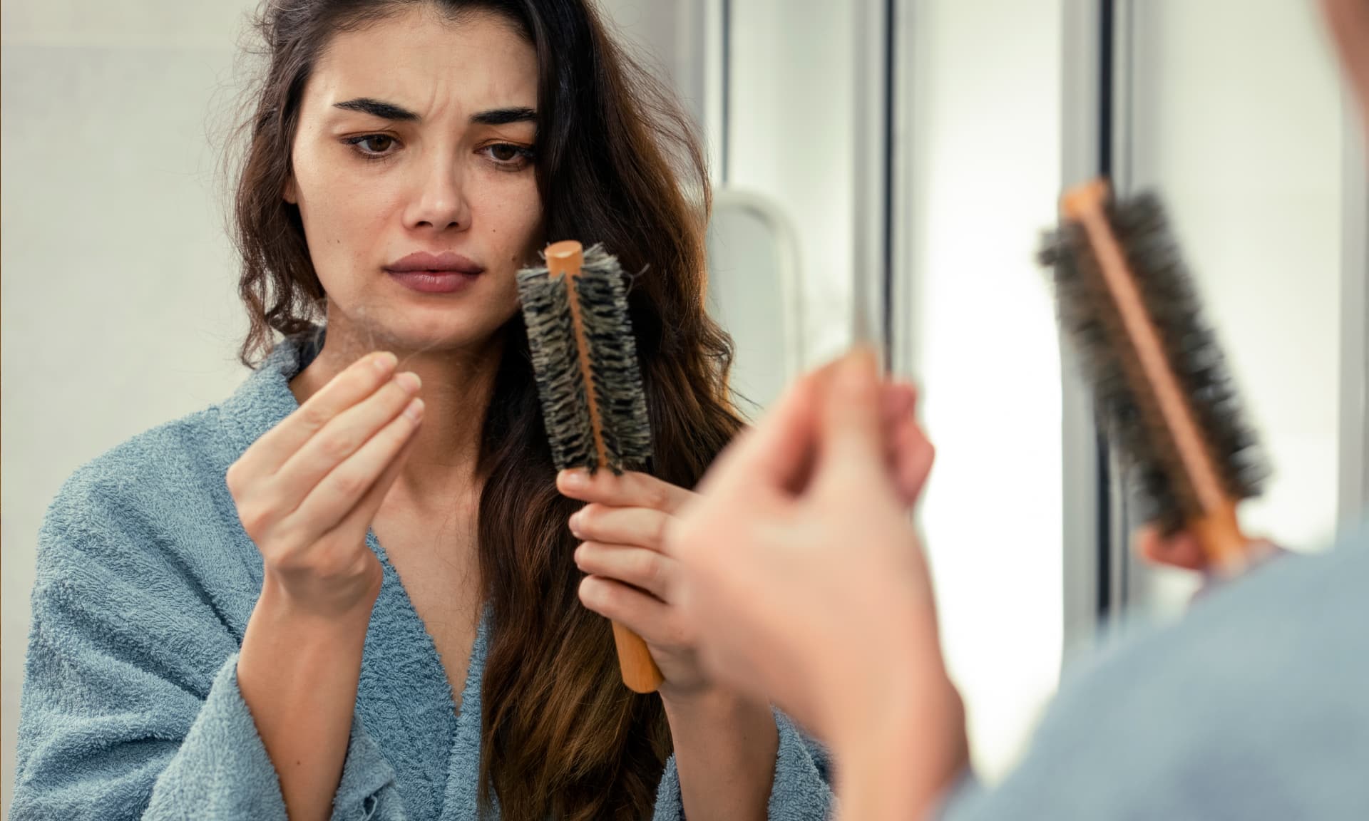 A woman pulling hair off her hairbrush