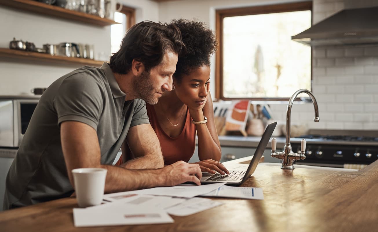couple in kitchen looking at laptop