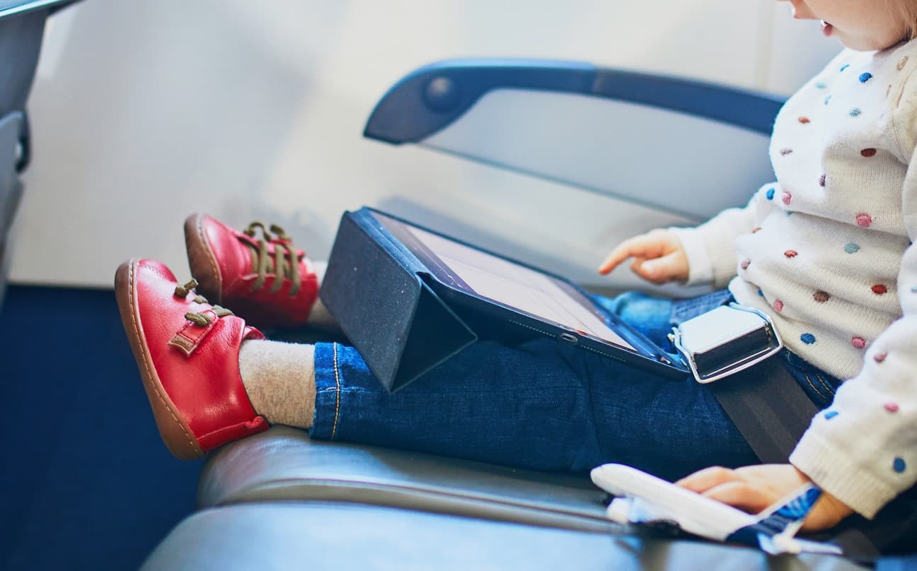 child sitting in vehicle with a tablet