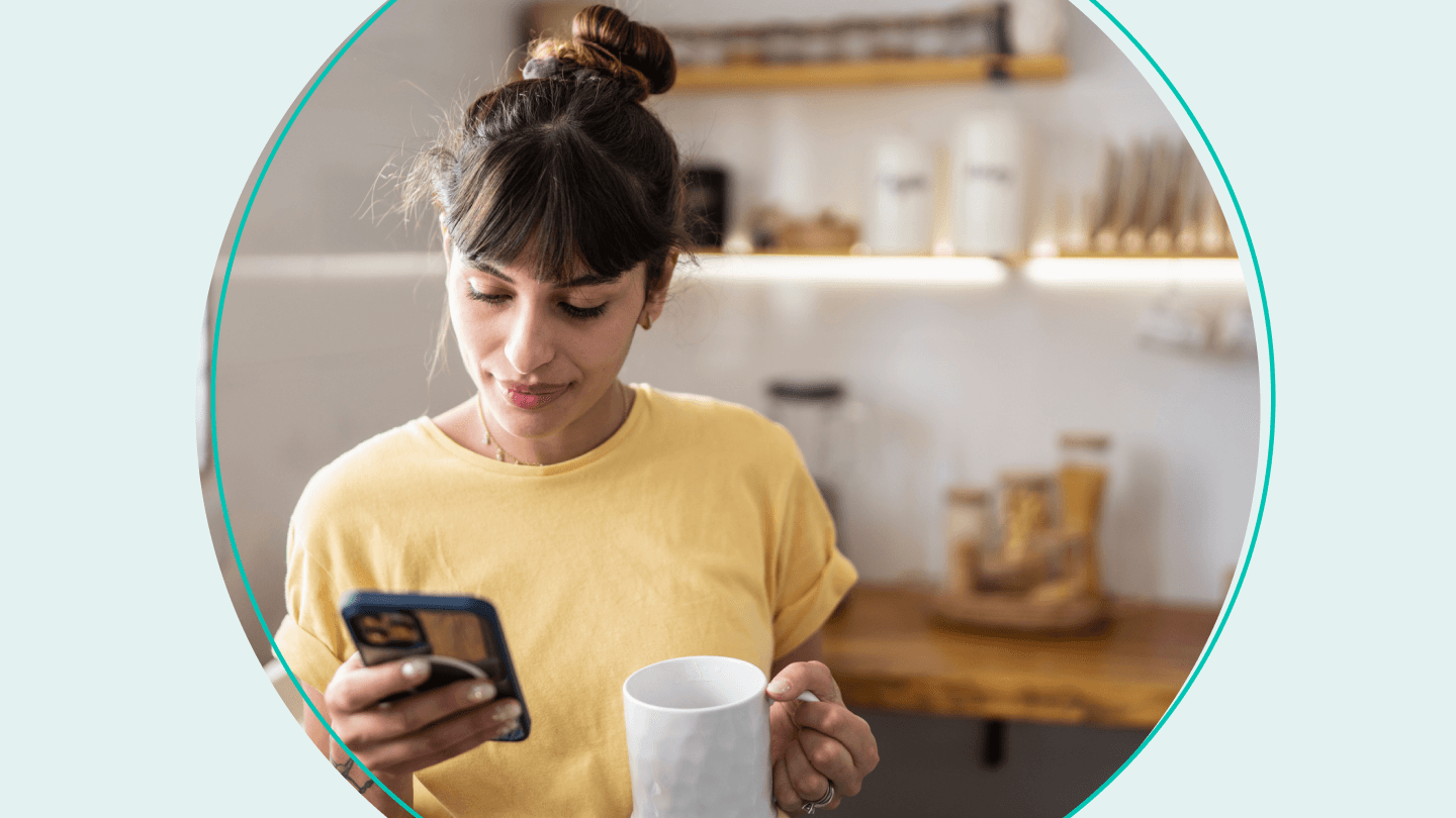 woman holding coffee and looking at phone