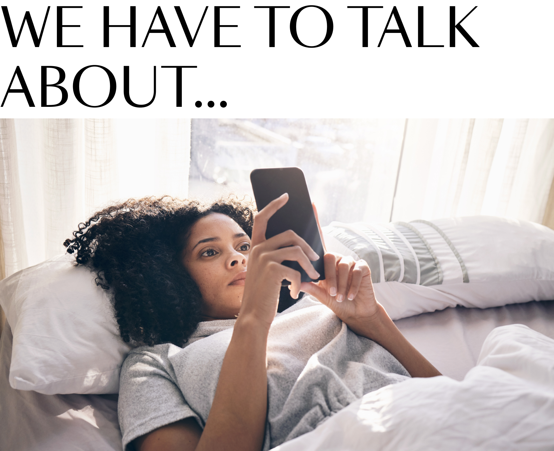 A woman laying in bed looking at her phone