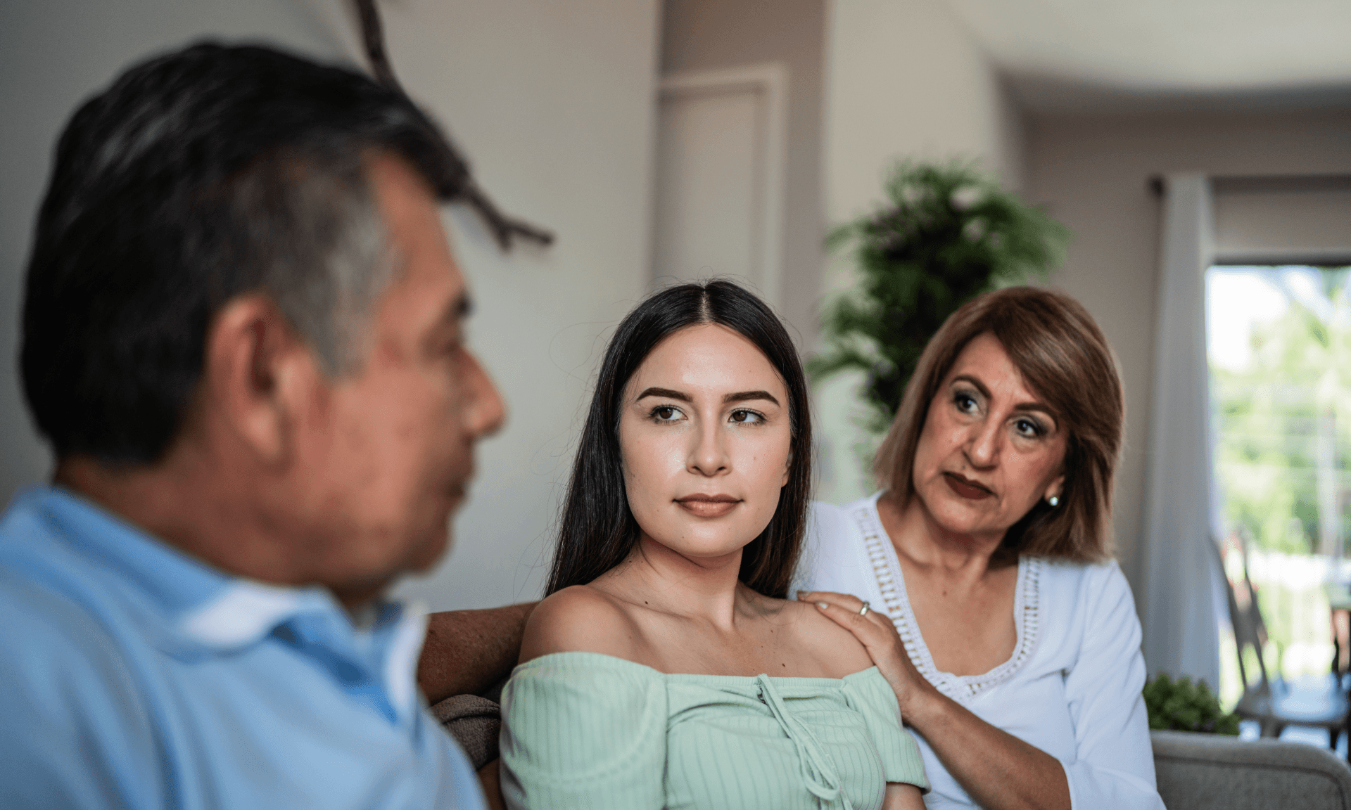 A mother and daughter looking at a father on a couch