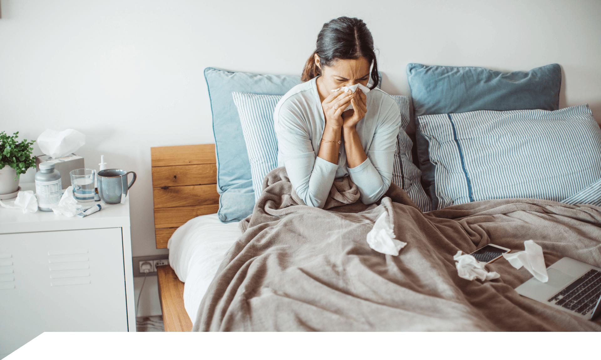 A woman in bed blowing her nose