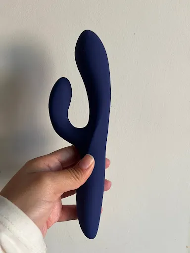 Woman holding purple rabbit vibrator against wall