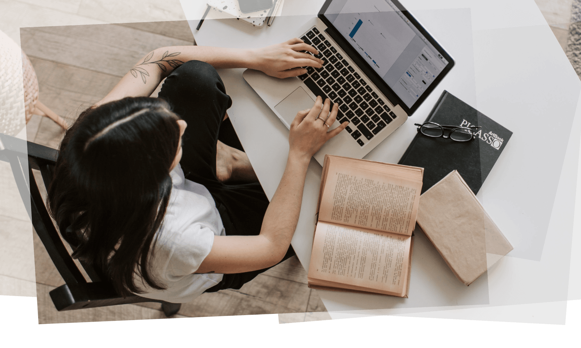 Aerial view of a woman sitting at a desk working on her laptop with books on the desk next to her