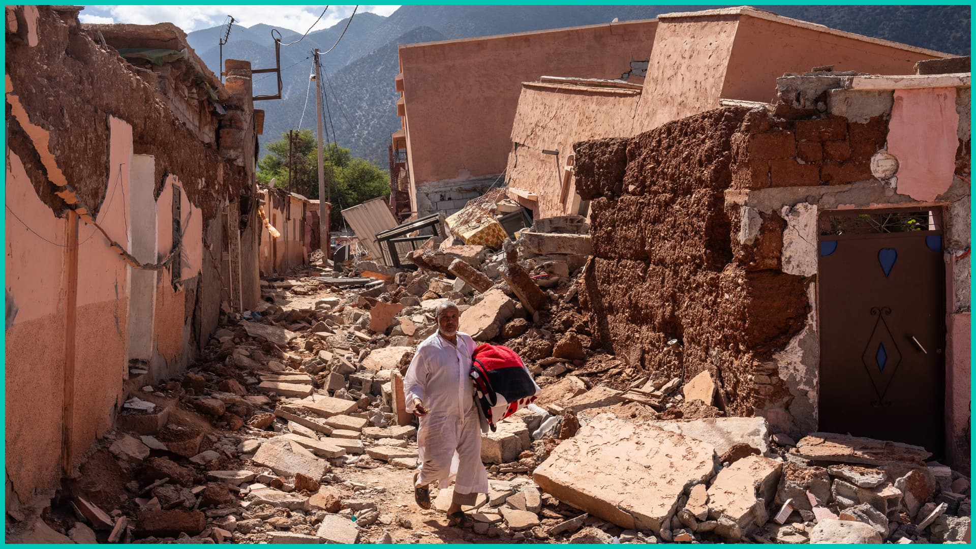 A man carries a blanket as he walks over the rubble of buildings destroyed in yesterday's earthquake, on September 10, 2023 in Ouirgane, Morocco