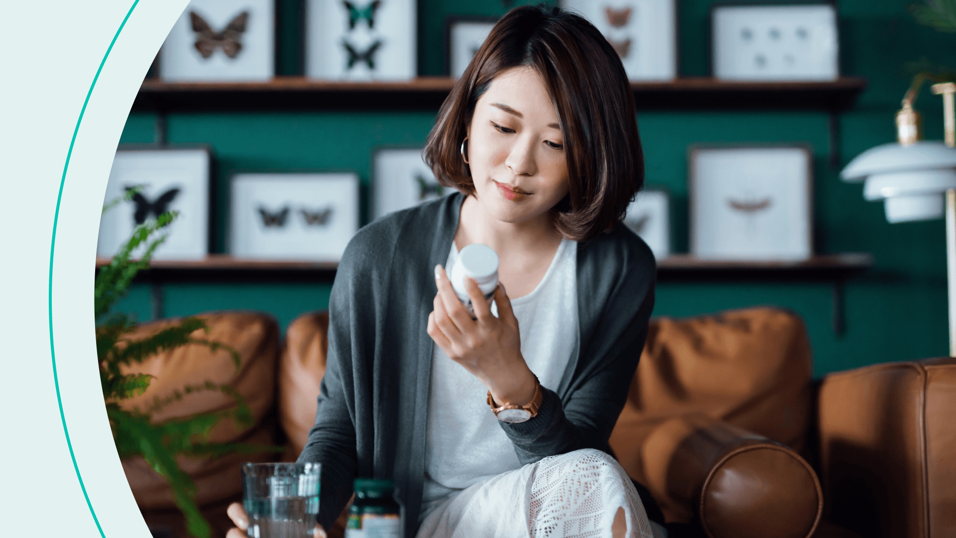 woman looking at pill bottle with glass of water in hand
