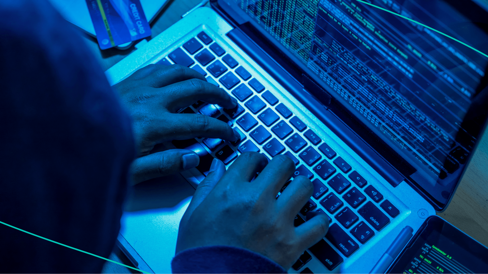 Person in black hood typing on laptop