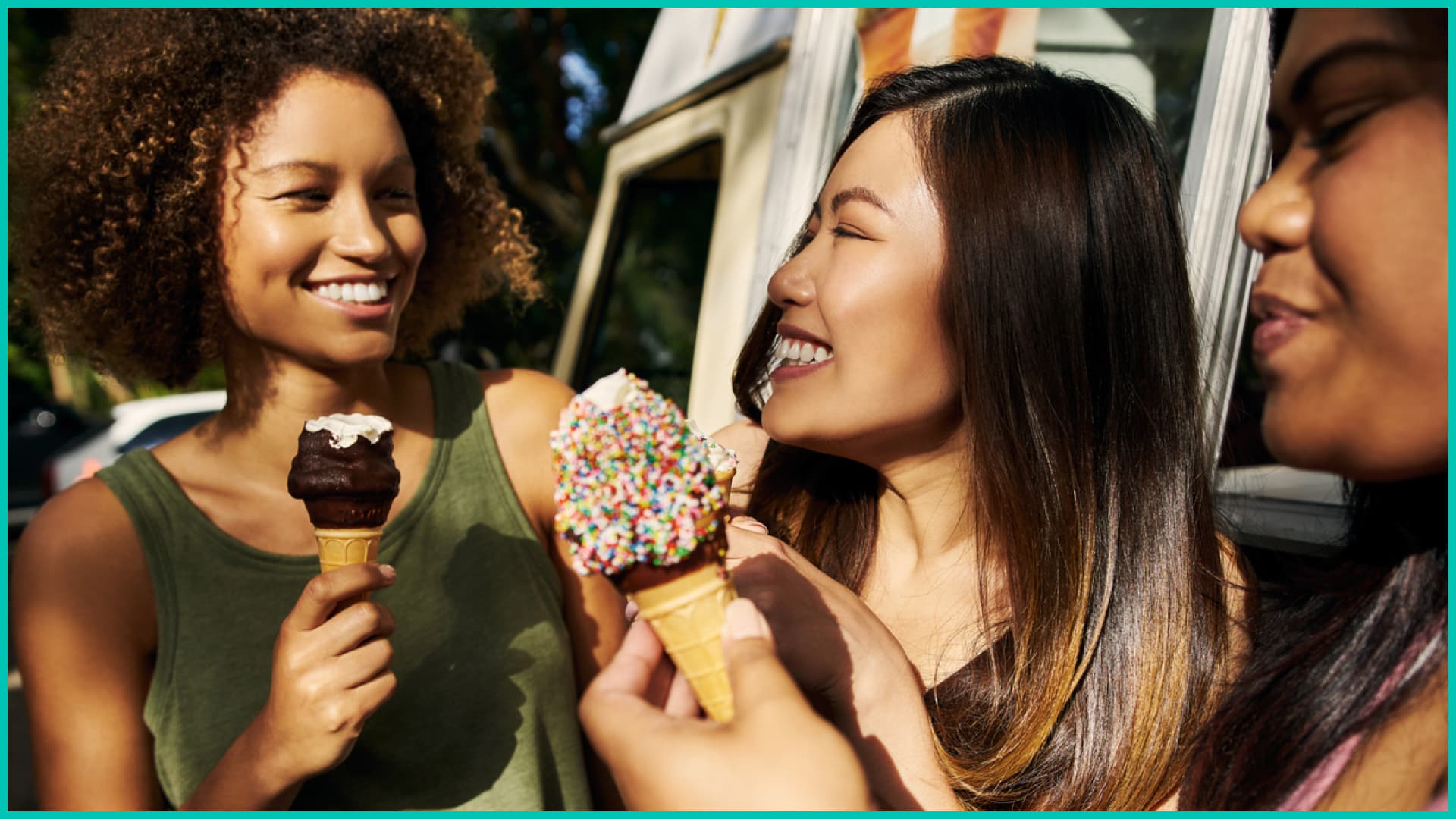 Three women smiling and eating ice cream outside