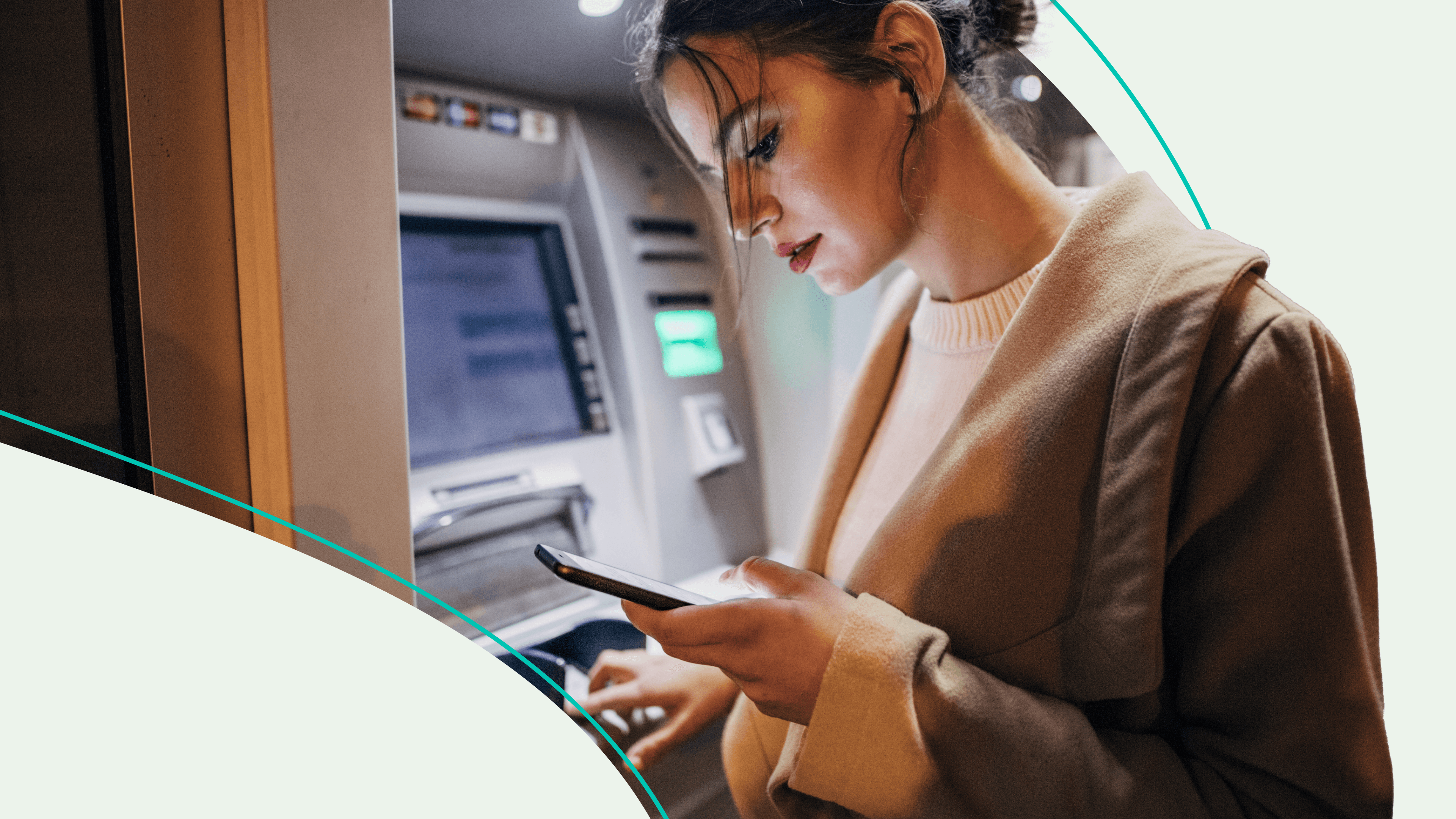 A woman looking at her phone in front of an ATM
