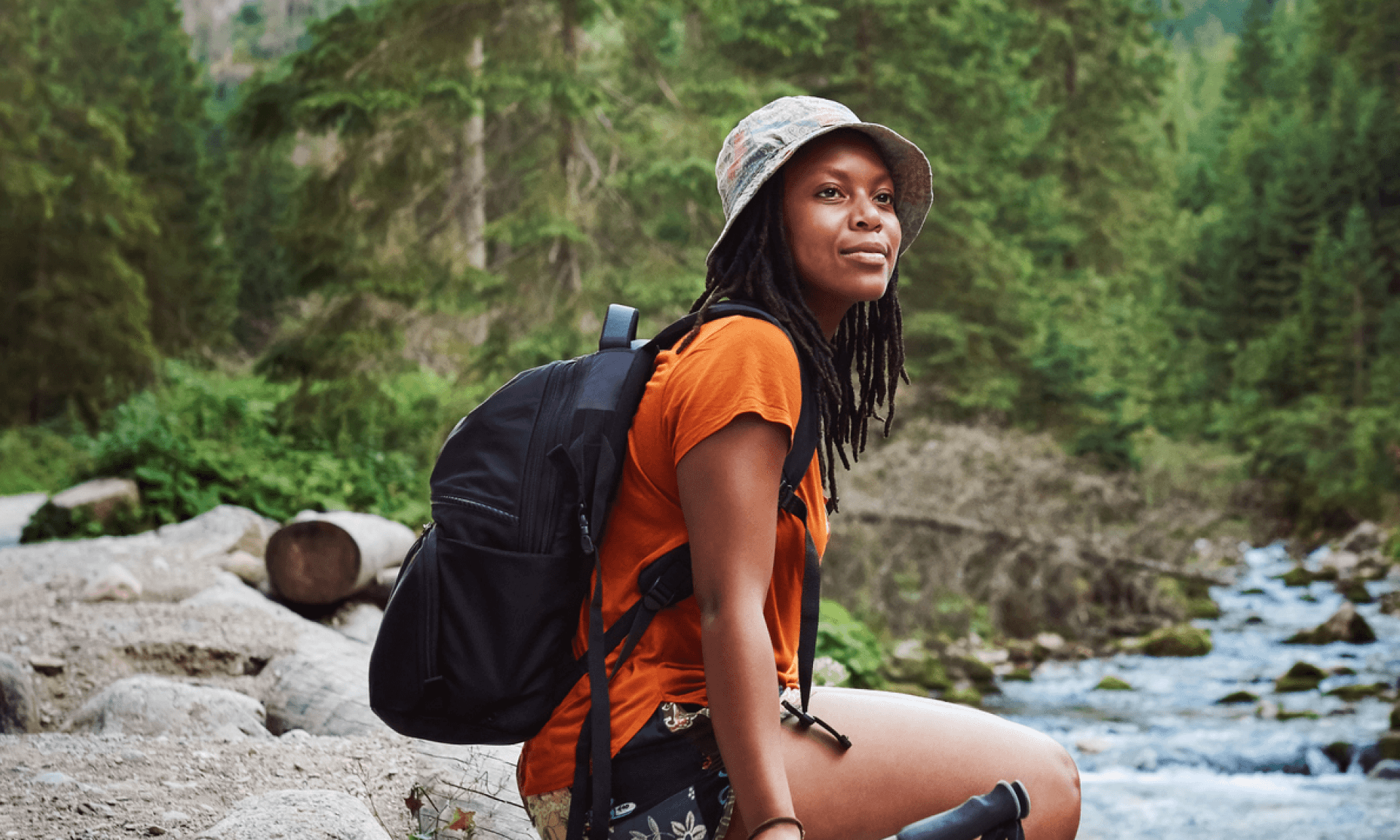 A woman sitting on a rock by a river