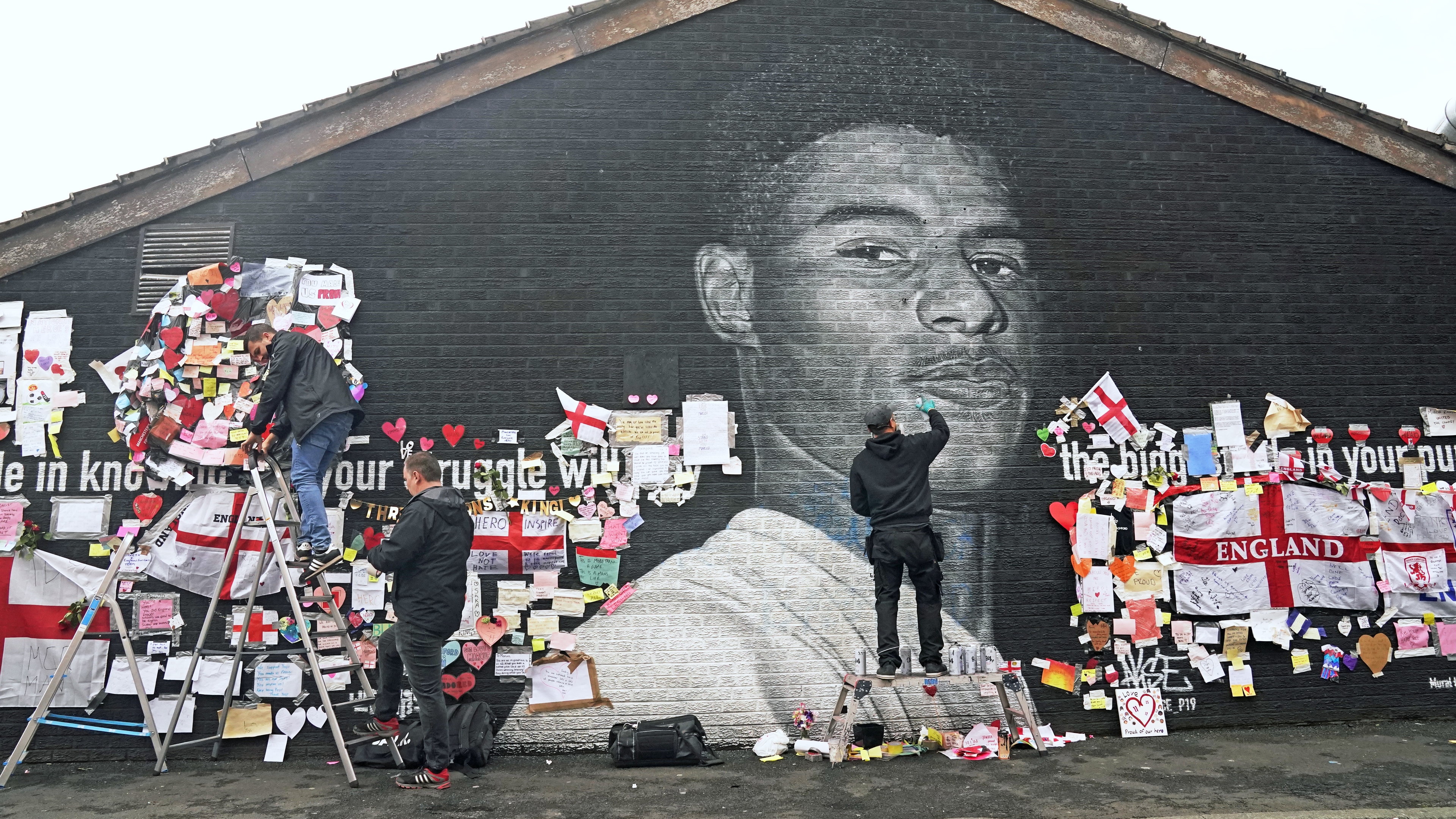 Street artist Akse P19 repairs the mural of Manchester United striker and England player Marcus Rashford