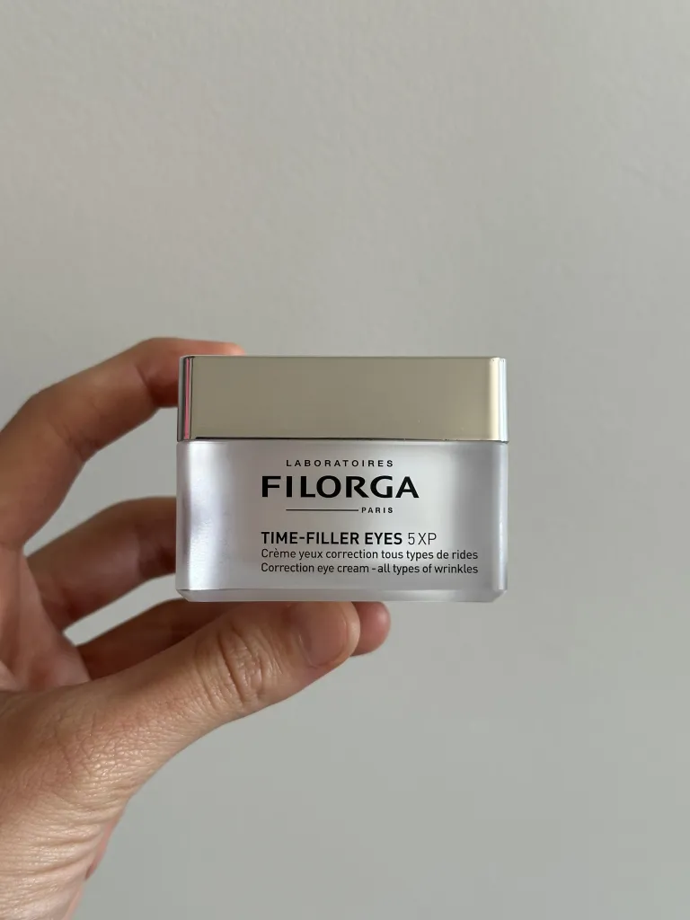 Hand holding opaque jar of eye cream