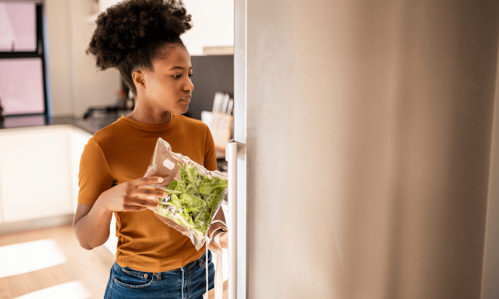 A woman standing in front of her fridge deciding what to eat