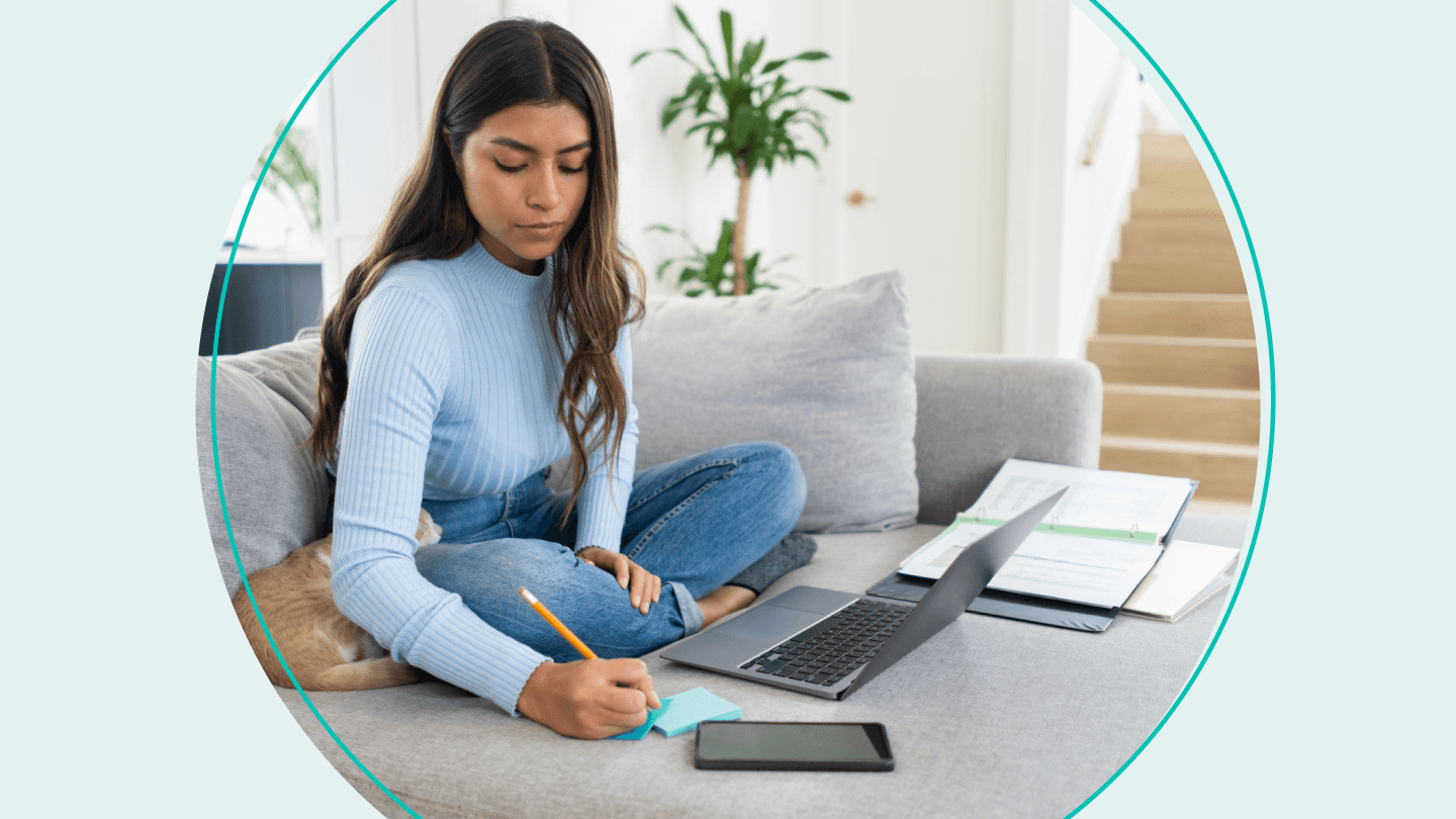 woman sitting on couch with laptop and binder