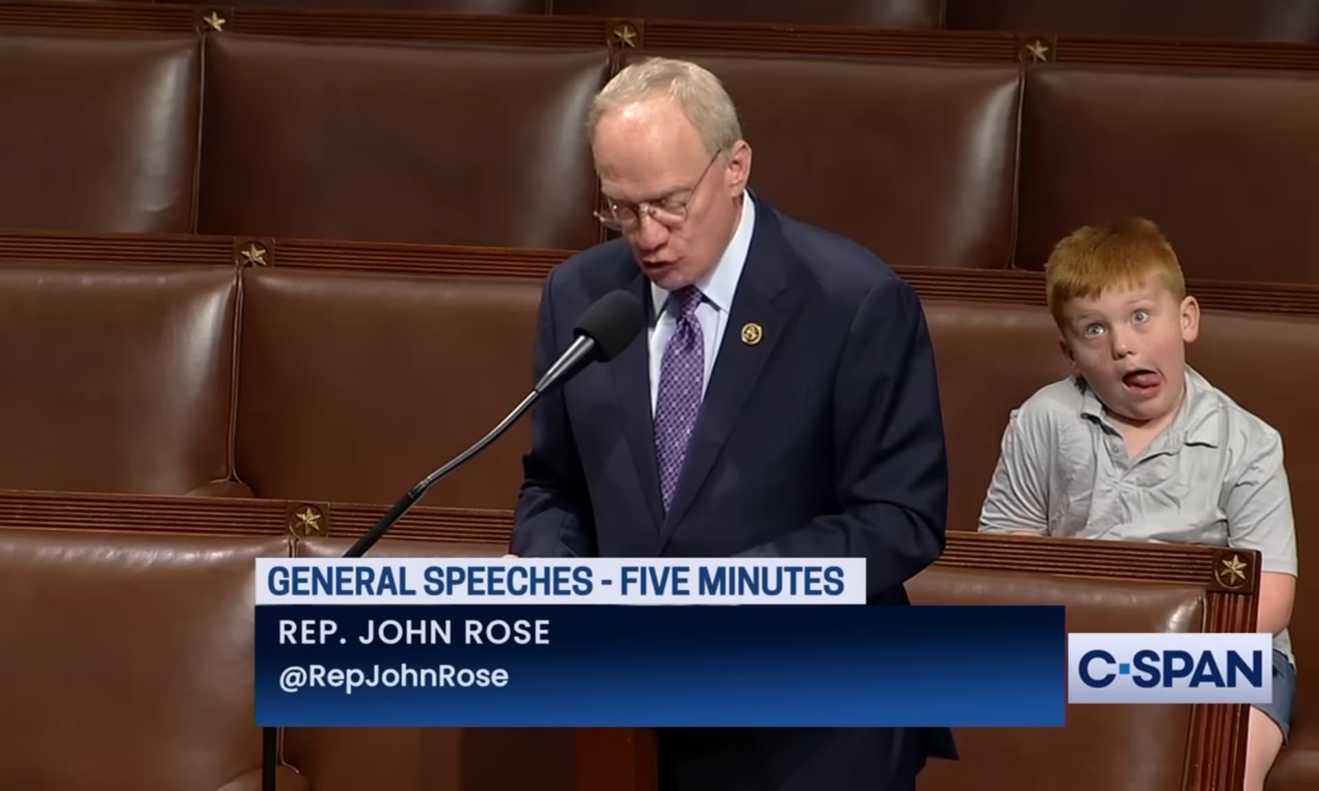 Representative John Rose (R-TN) delivering a floor speech, as his son, Guy Rose, makes funny faces.