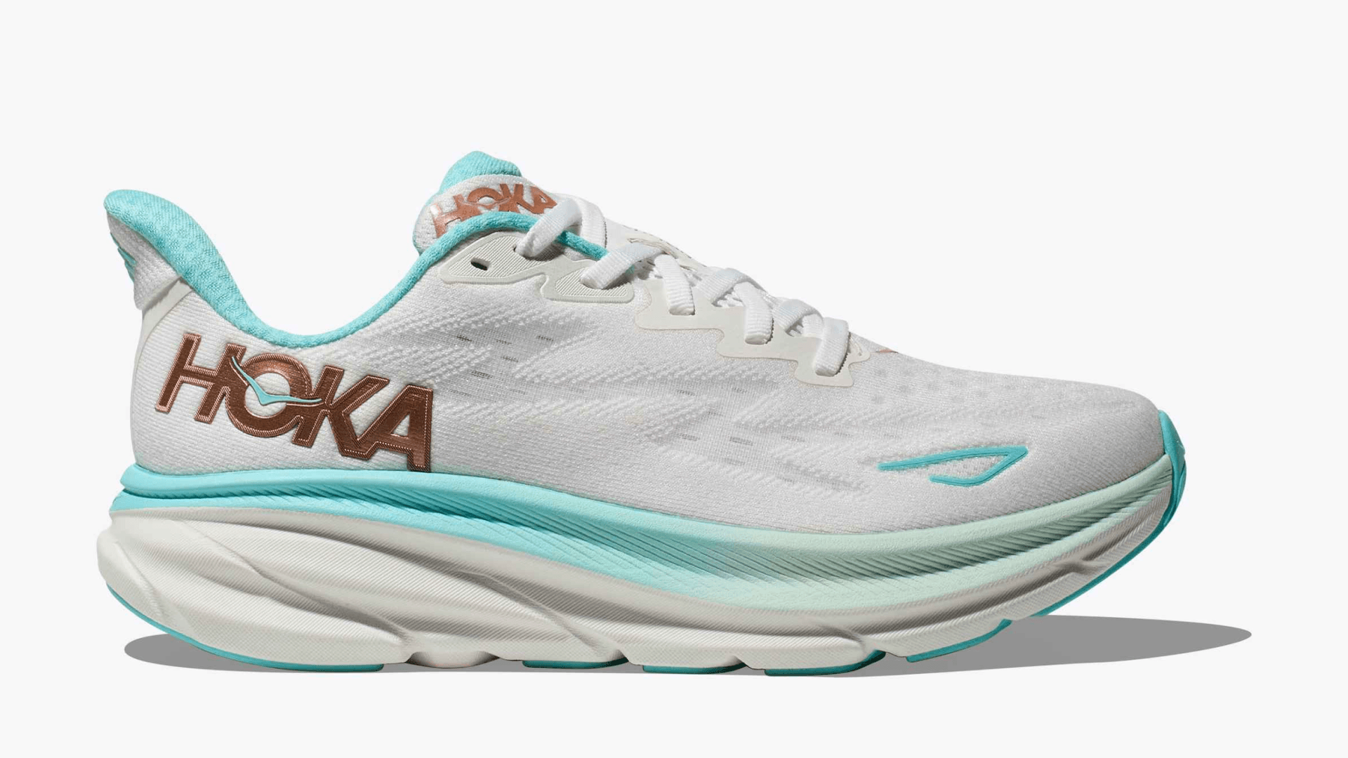 Light gray sneakers with rose gold "Hoka" logo and teal accents