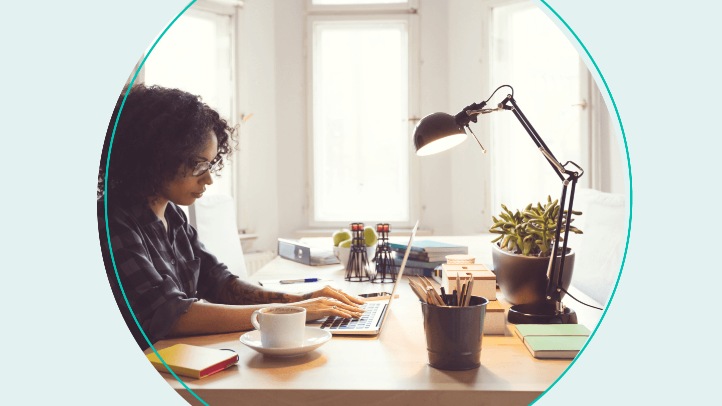 woman sitting at home office desk with laptop and plants