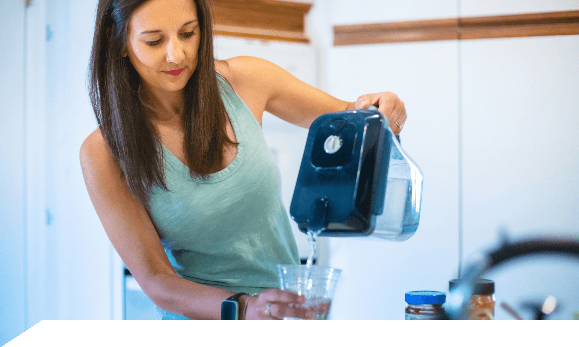 A woman pouring a glass of water from a filtered pitcher