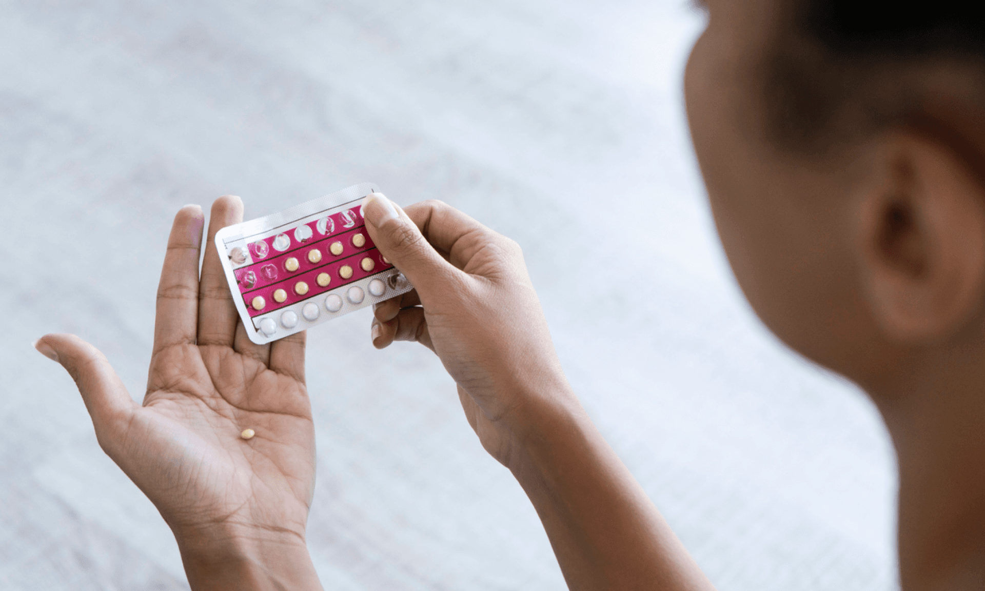 A woman holding a packet of birth control pills