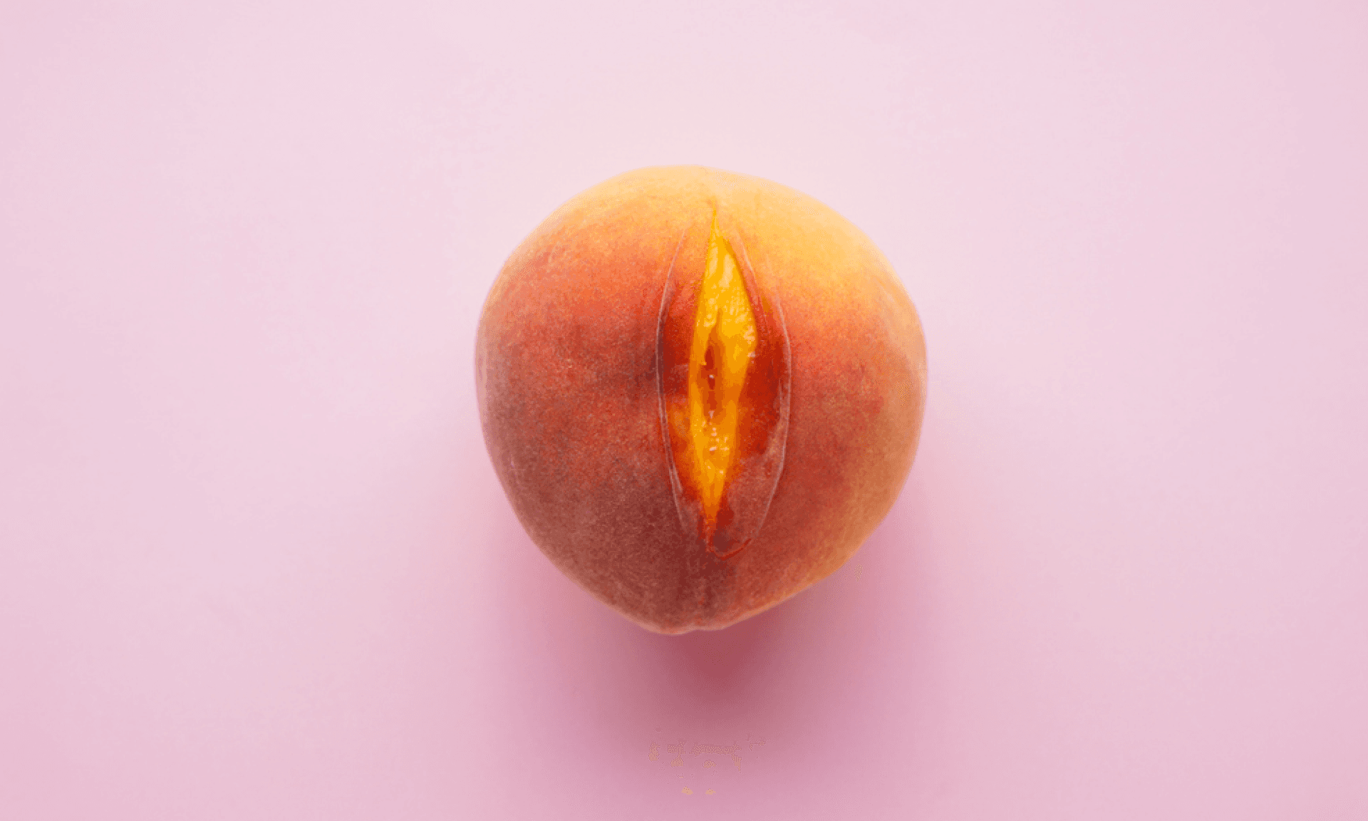 A peach slightly cut to look like a vulva on a pink background