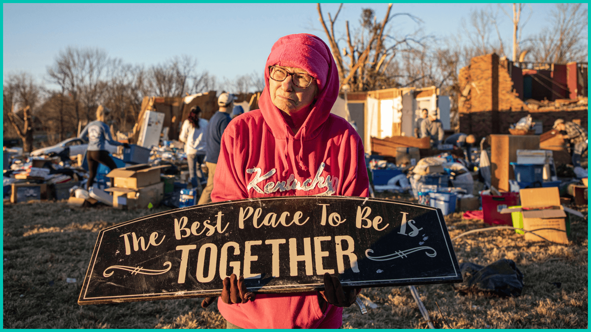 Kitty Williams Holds up a sign that survived the storm as her friends and family help gather her belongings of what is left of his house after extreme weather hit the area,