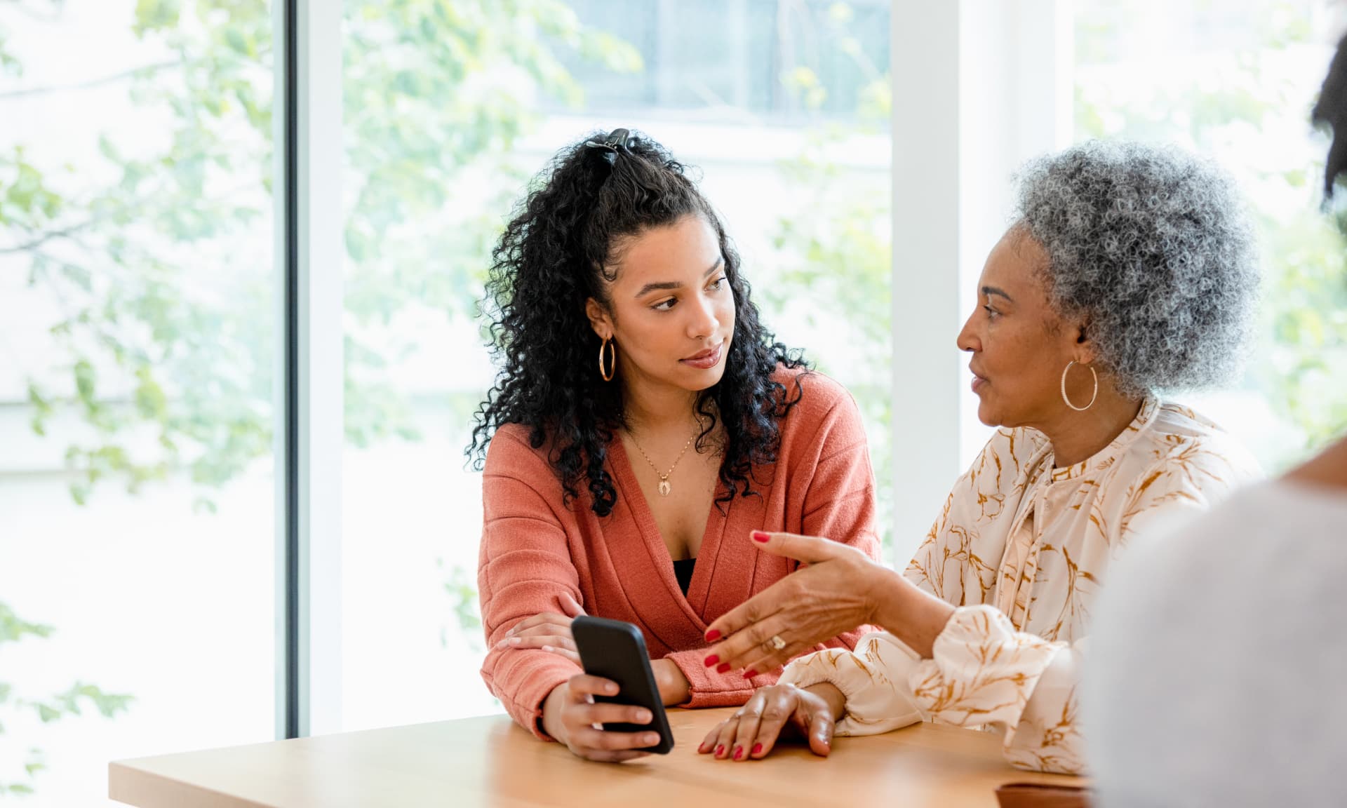 Woman and her mother looking at a cell phone together while sitting at a table