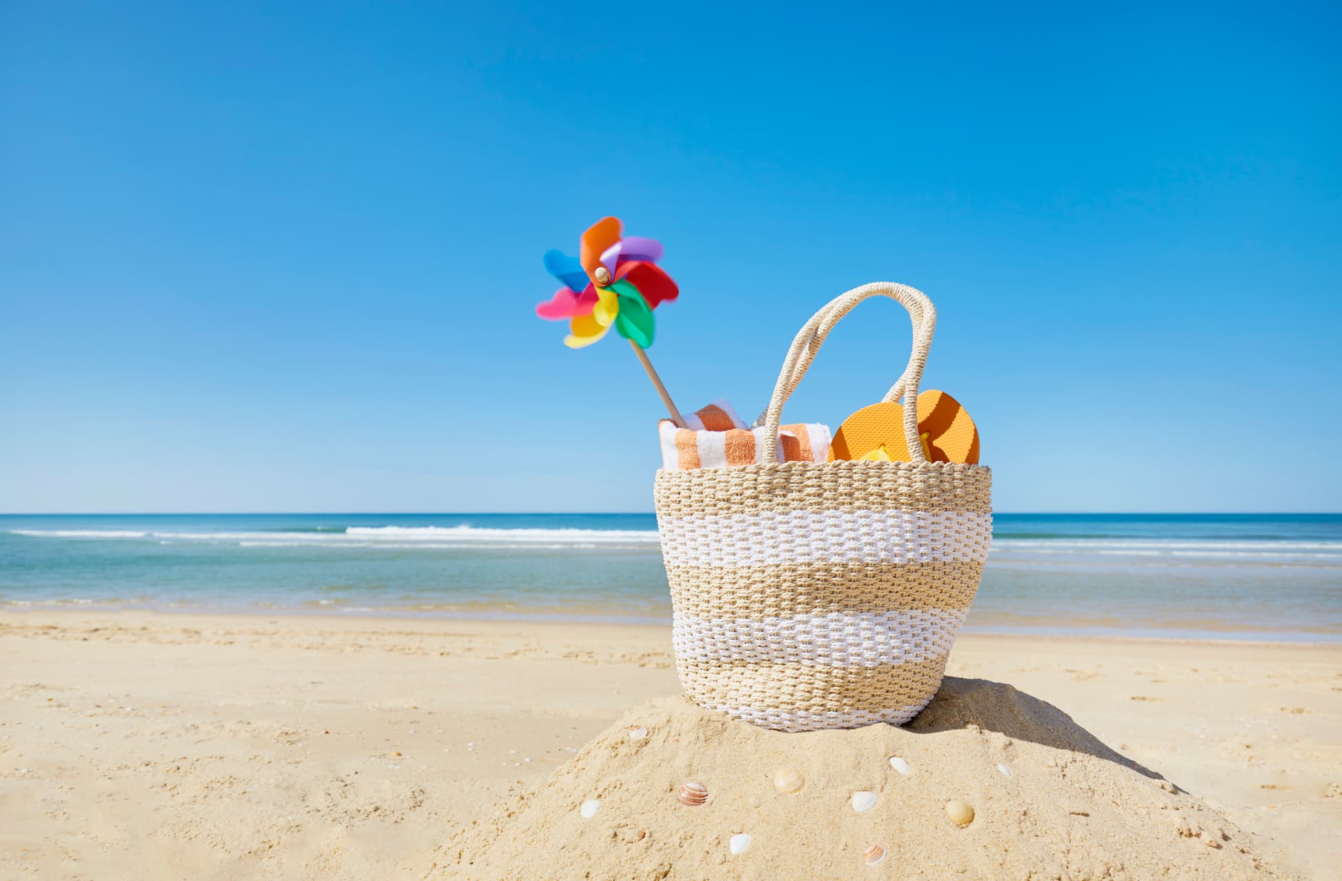 Beach bag and colorful pinwheel at sea against blue sky