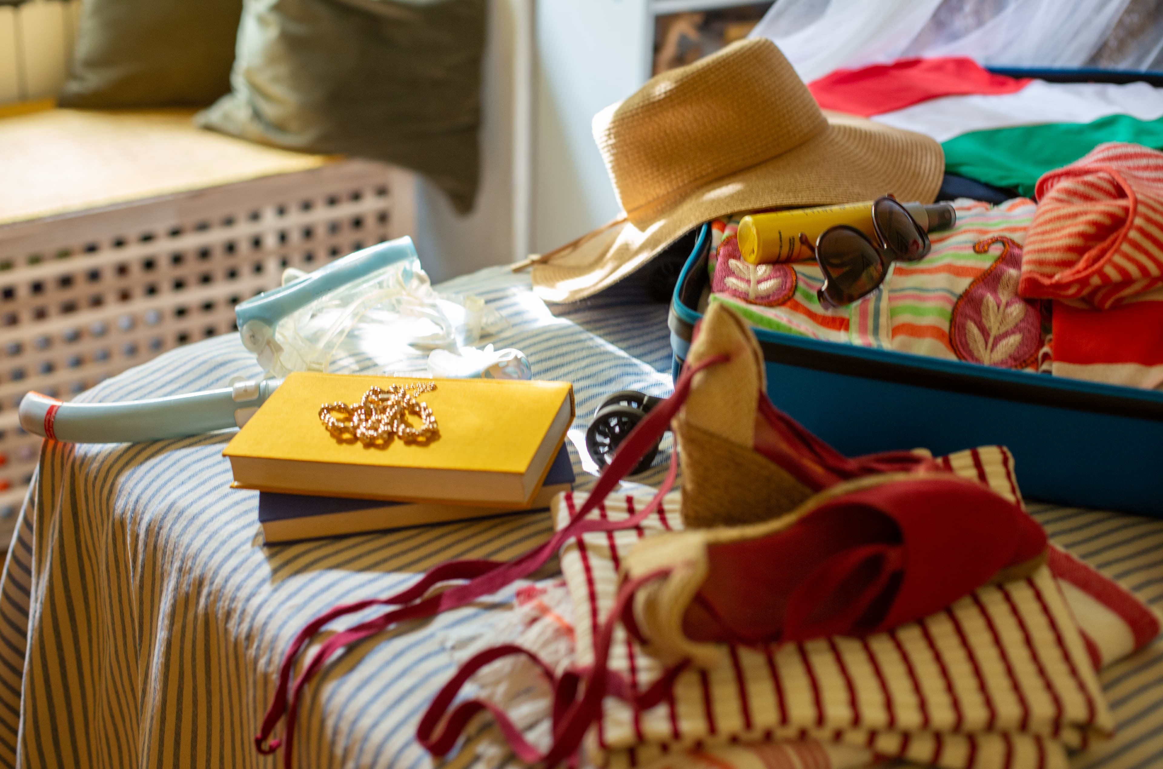 An open suitcase full of summer clothing and accessories.