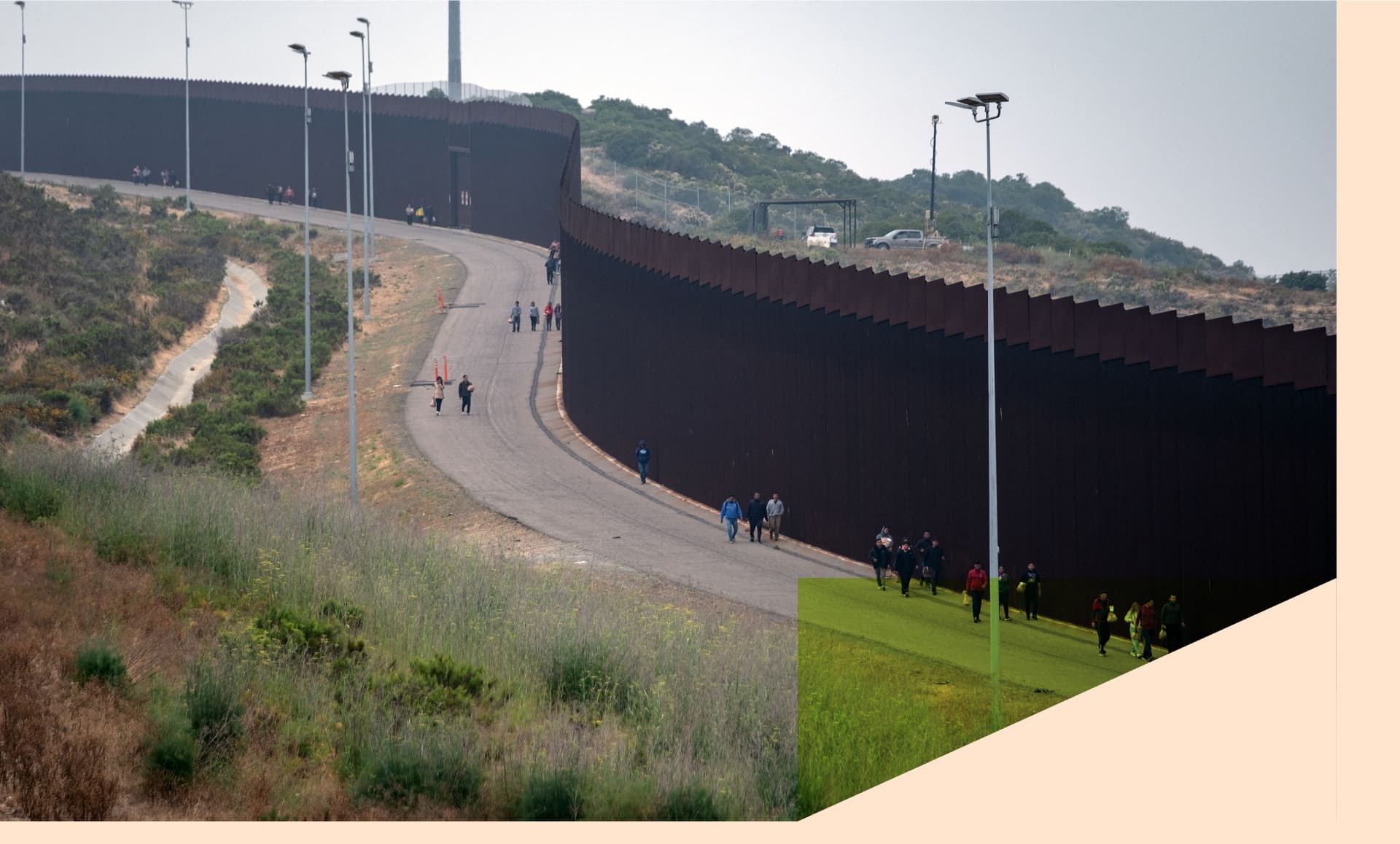 Migrants and asylum seekers walk to be processed by the Border Patrol between fences at the US-Mexico