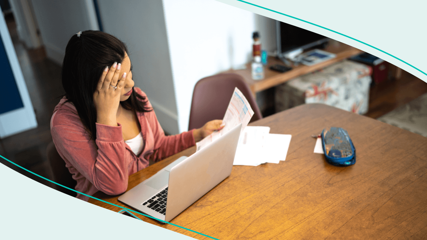 woman sitting at table with laptop looking over bills