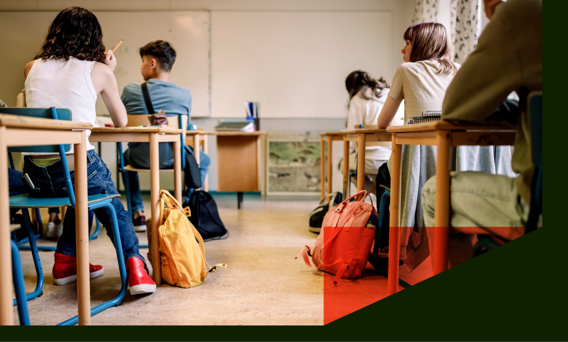 Multiracial group of students sitting at desk in classroom - stock photo