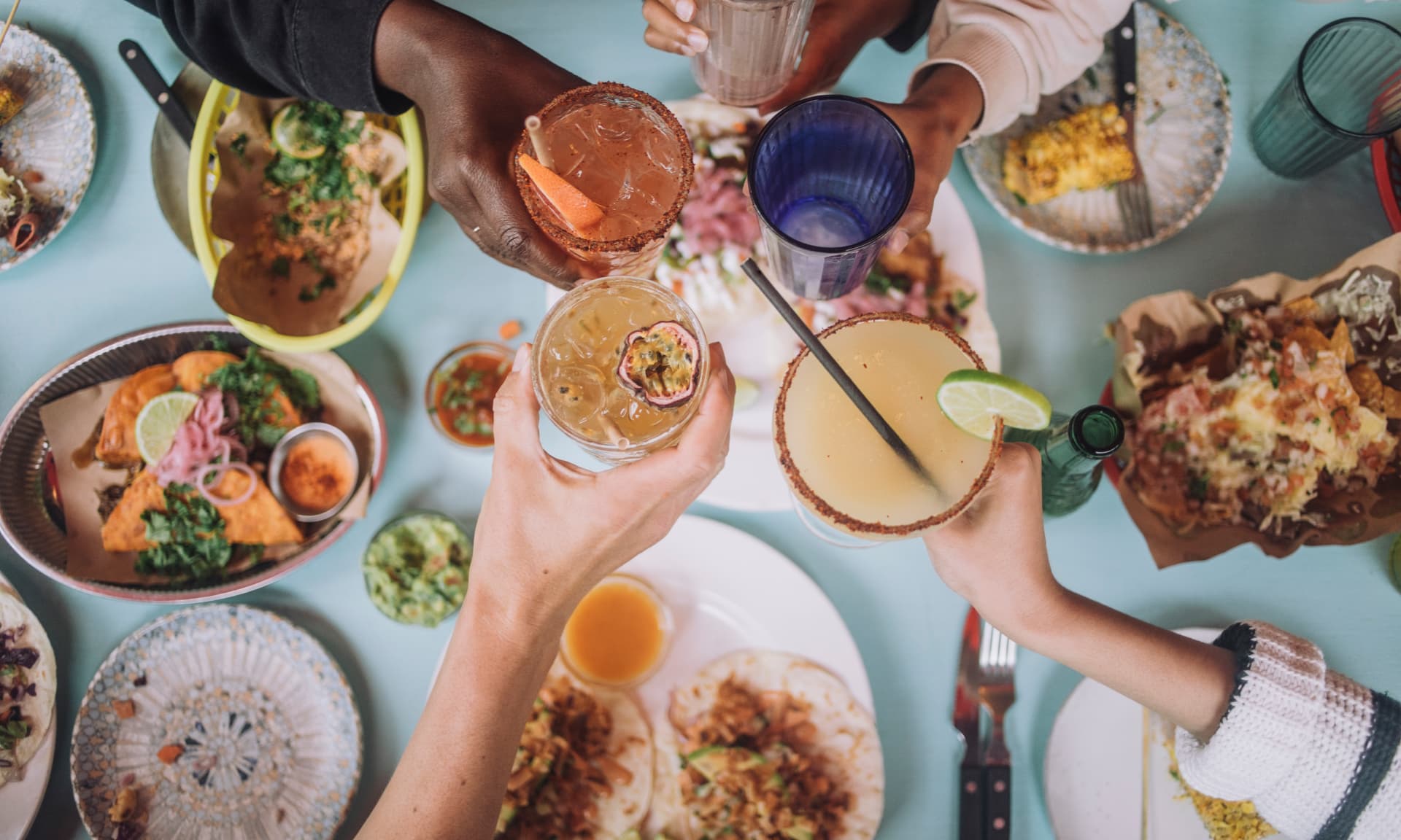 Directly above view of hands toasting glass of fresh cocktails while celebrating at restaurant