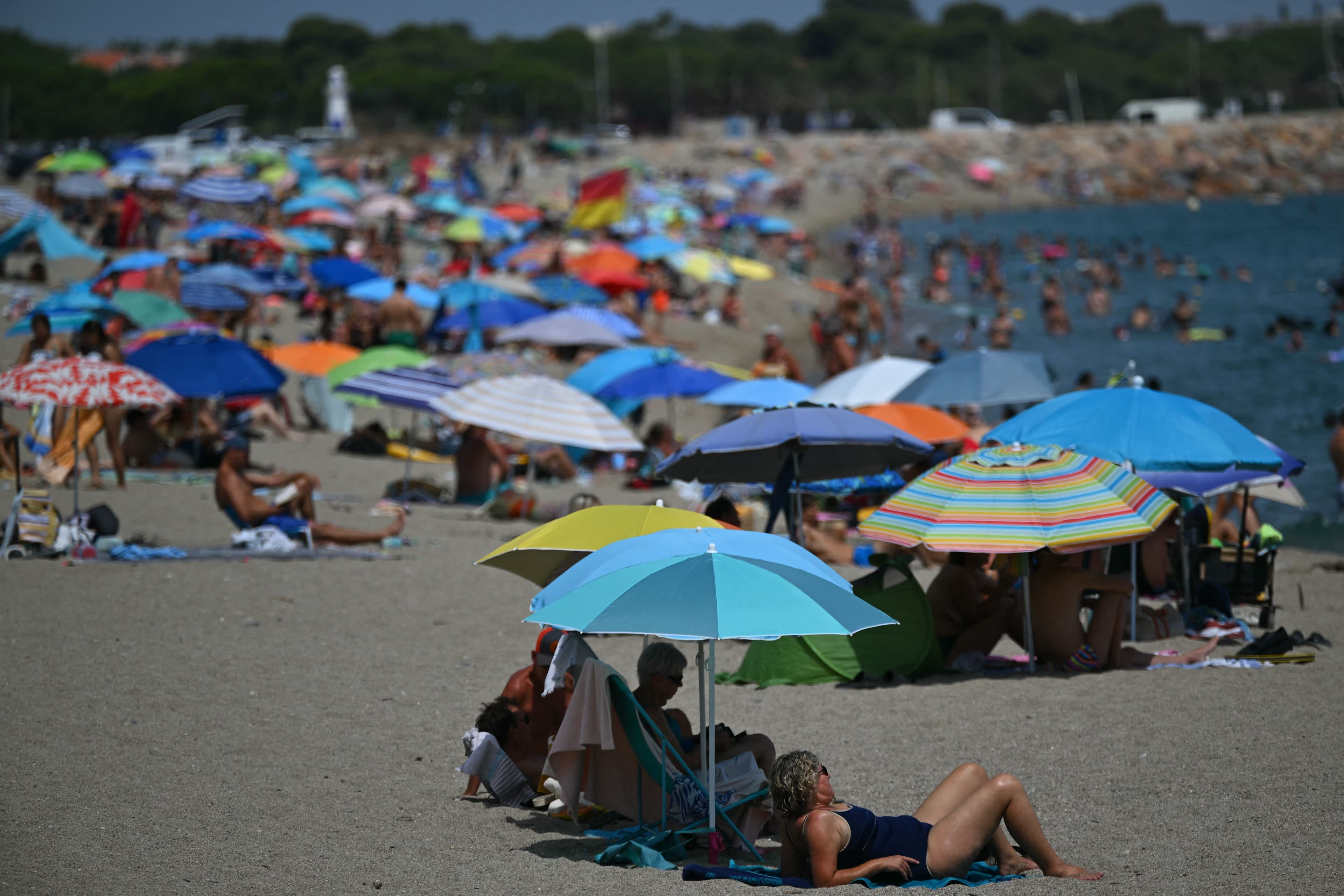 Beachgoers under umbrellas of various colors