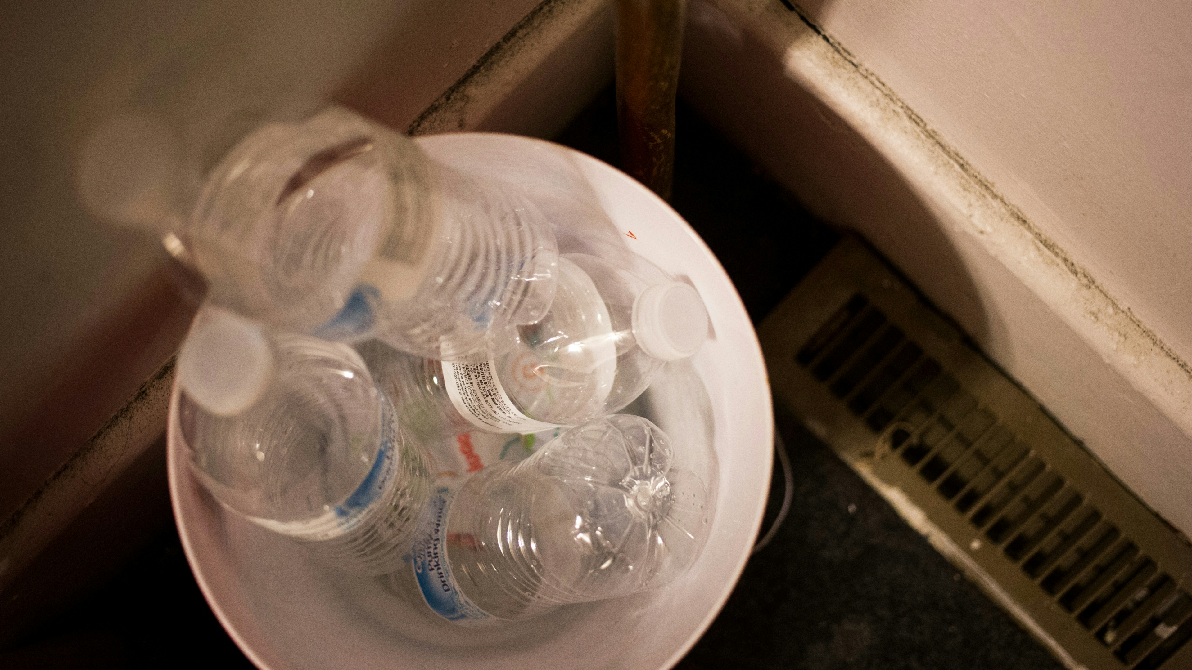 Bottles of water lay stacked in a trashcan