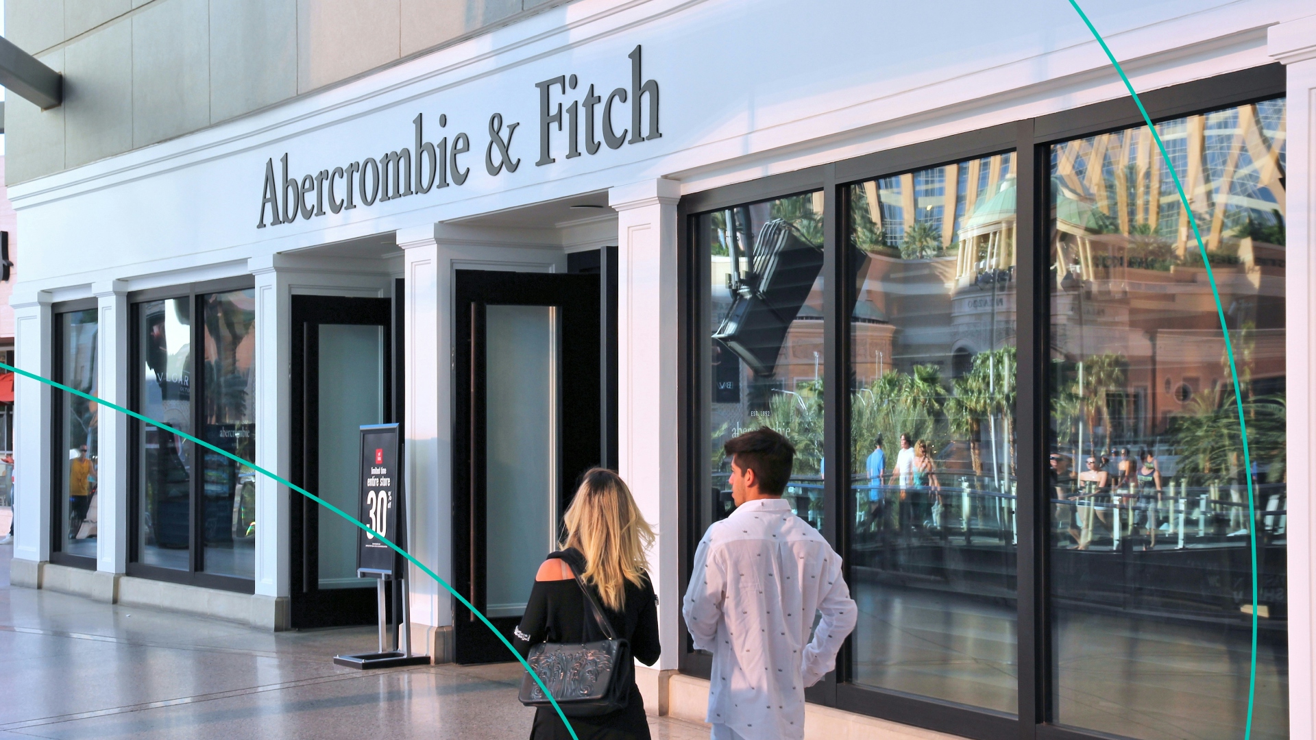 Two people walking in front of an Abercrombie & Fitch store front