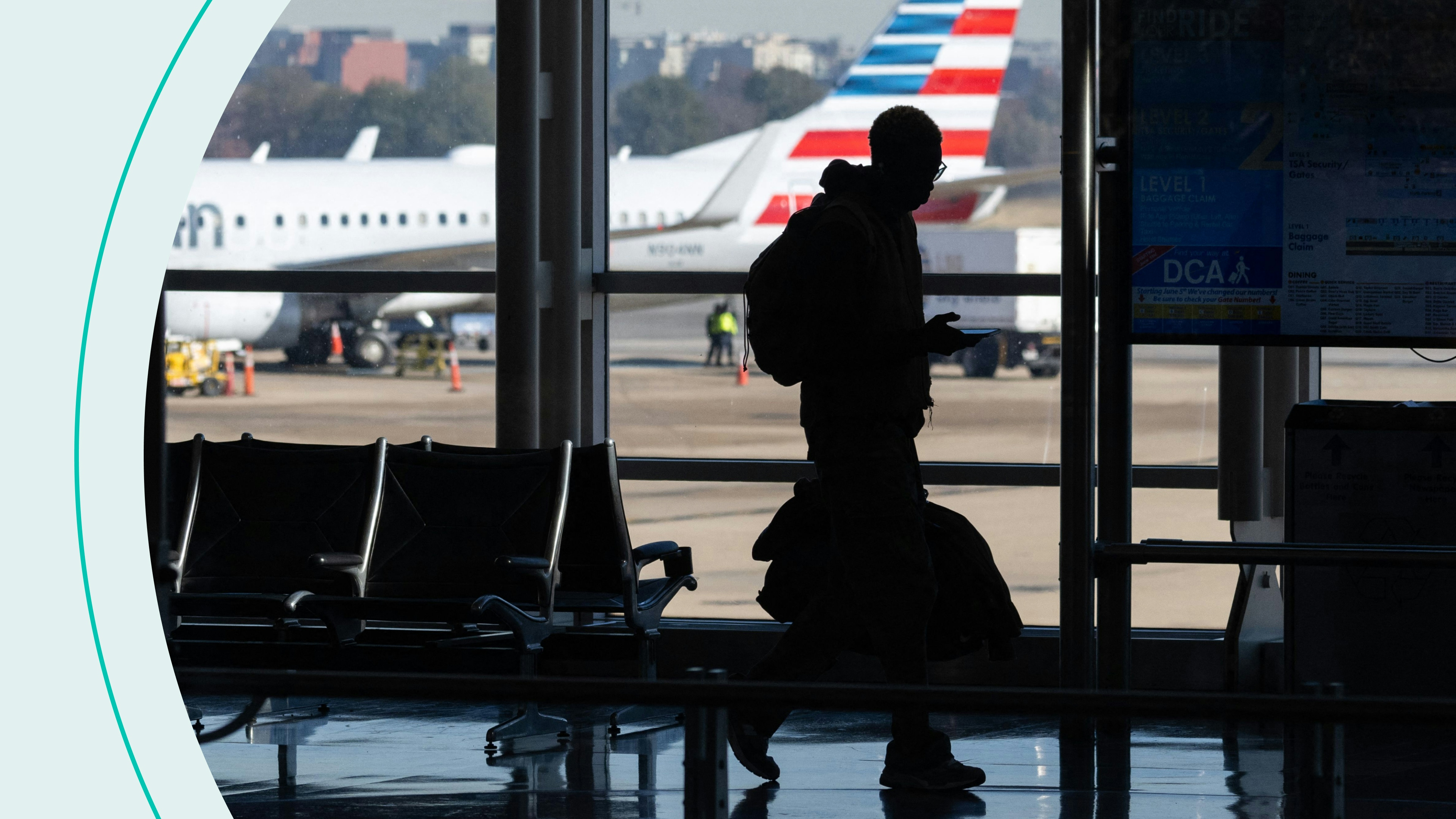 An American Airlines airplane is seen past a traveler walking through Ronald Reagan Washington National Airport in Arlington, Virginia, on November 22, 2022