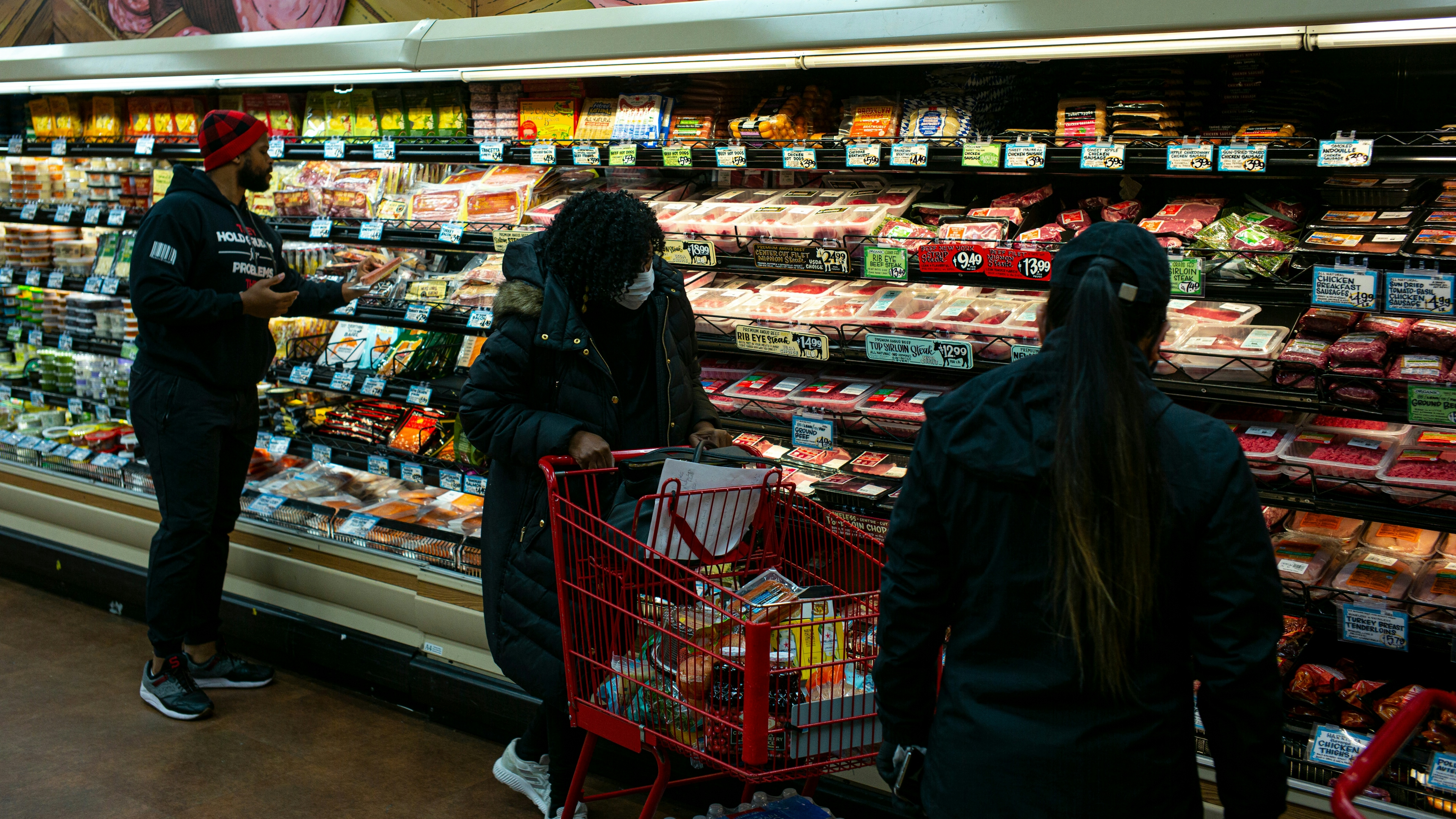 A shopper wearing a surgical mask, center, looks at looks at packaged meats at a Trader Joes in Brooklyn, New York.
