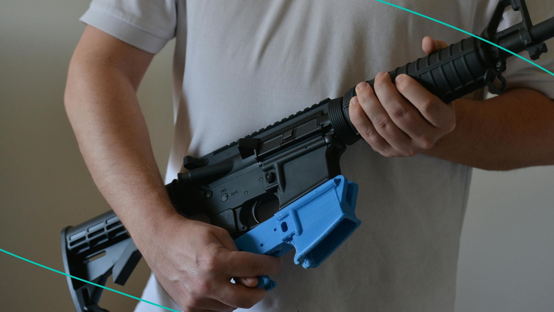 A man holds an AR-15 assault rifle along with a rifle's lower receiver made from a 3D printer