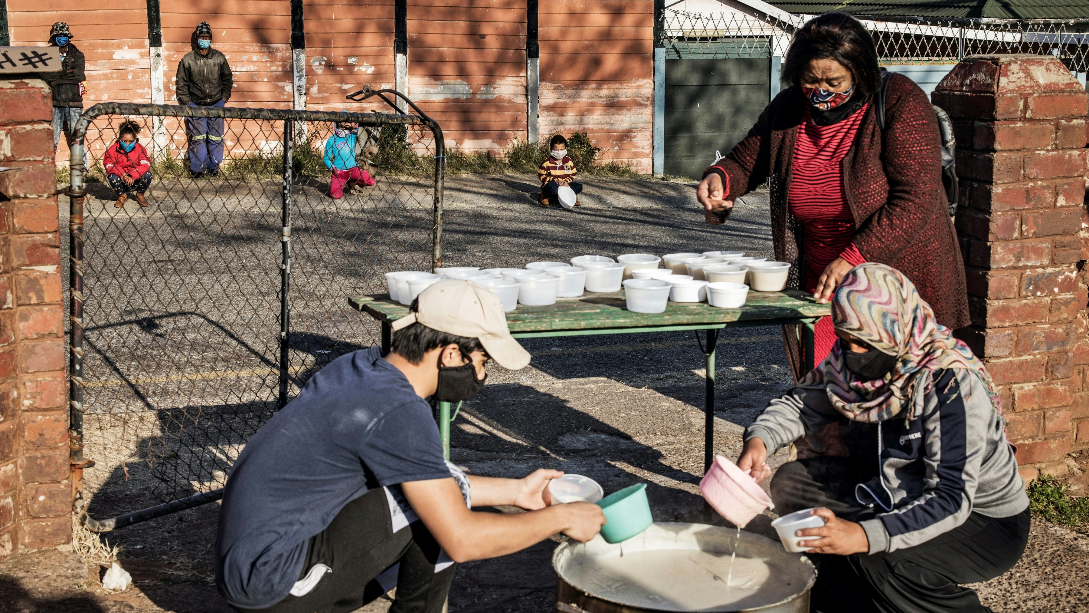Volunteers prepare portions of porridge to distribute to children for breakfast in Johannesburg