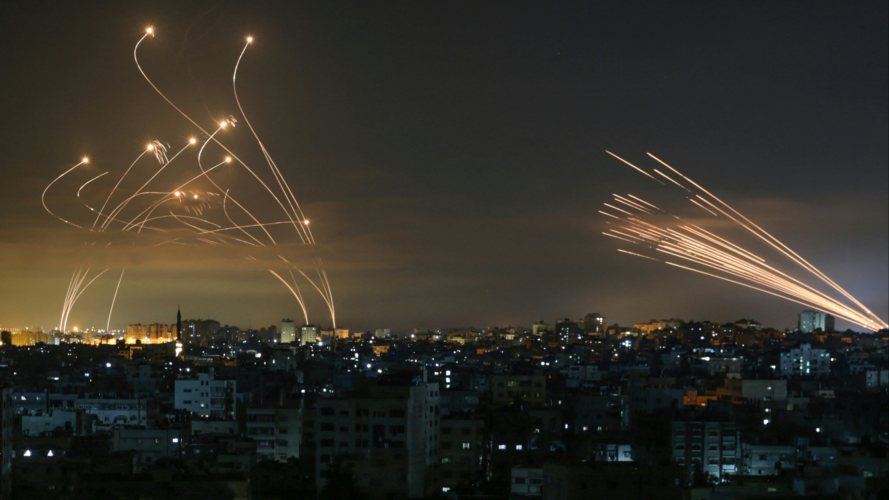 The Israeli Iron Dome missile defence system (L) intercepts rockets (R) fired by the Hamas movement towards southern Israel from Beit Lahia in the northern Gaza Strip as seen in the sky above the Gaza Strip overnight on May 14, 2021.