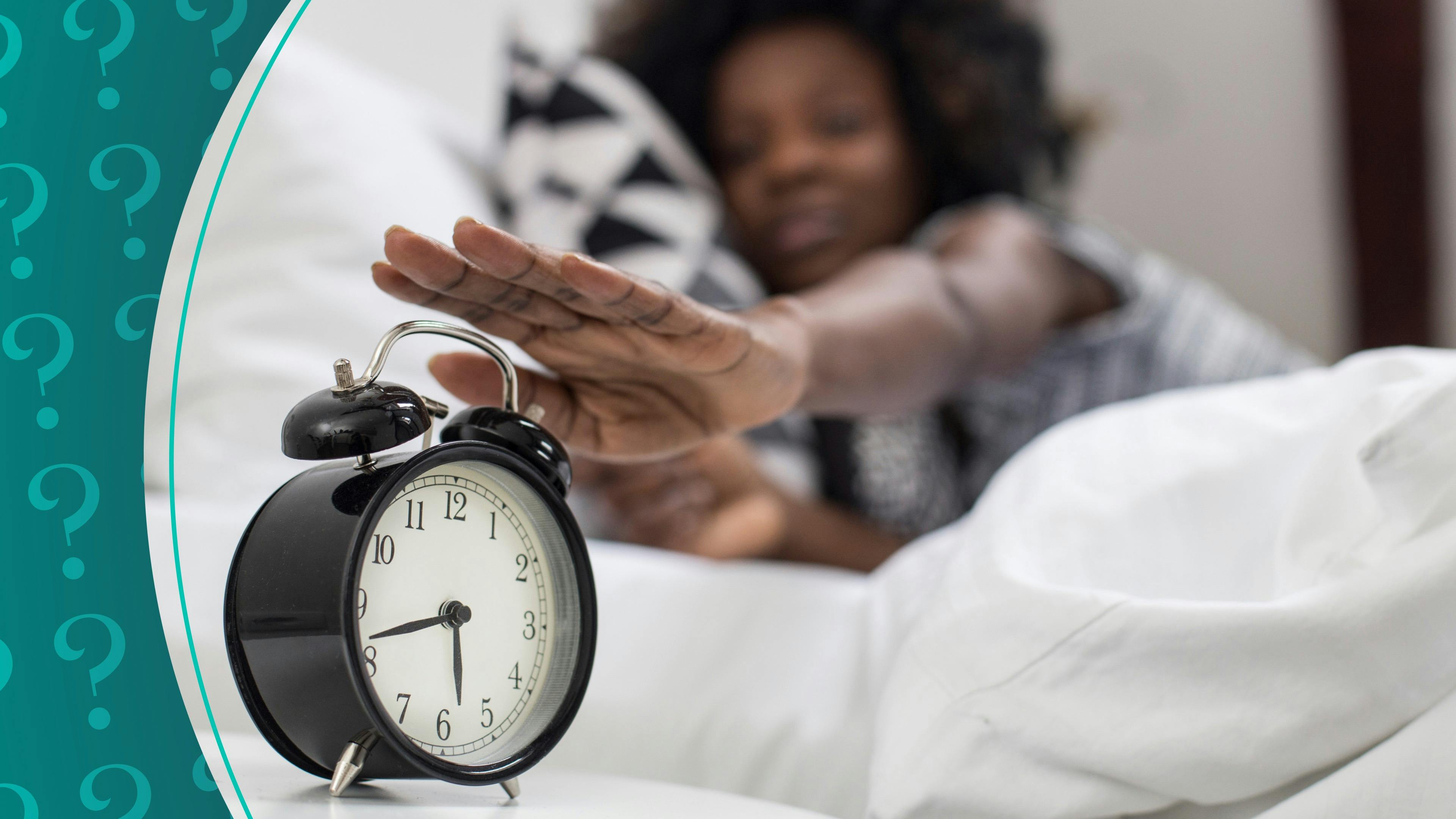 woman hitting snooze on alarm clock in bed
