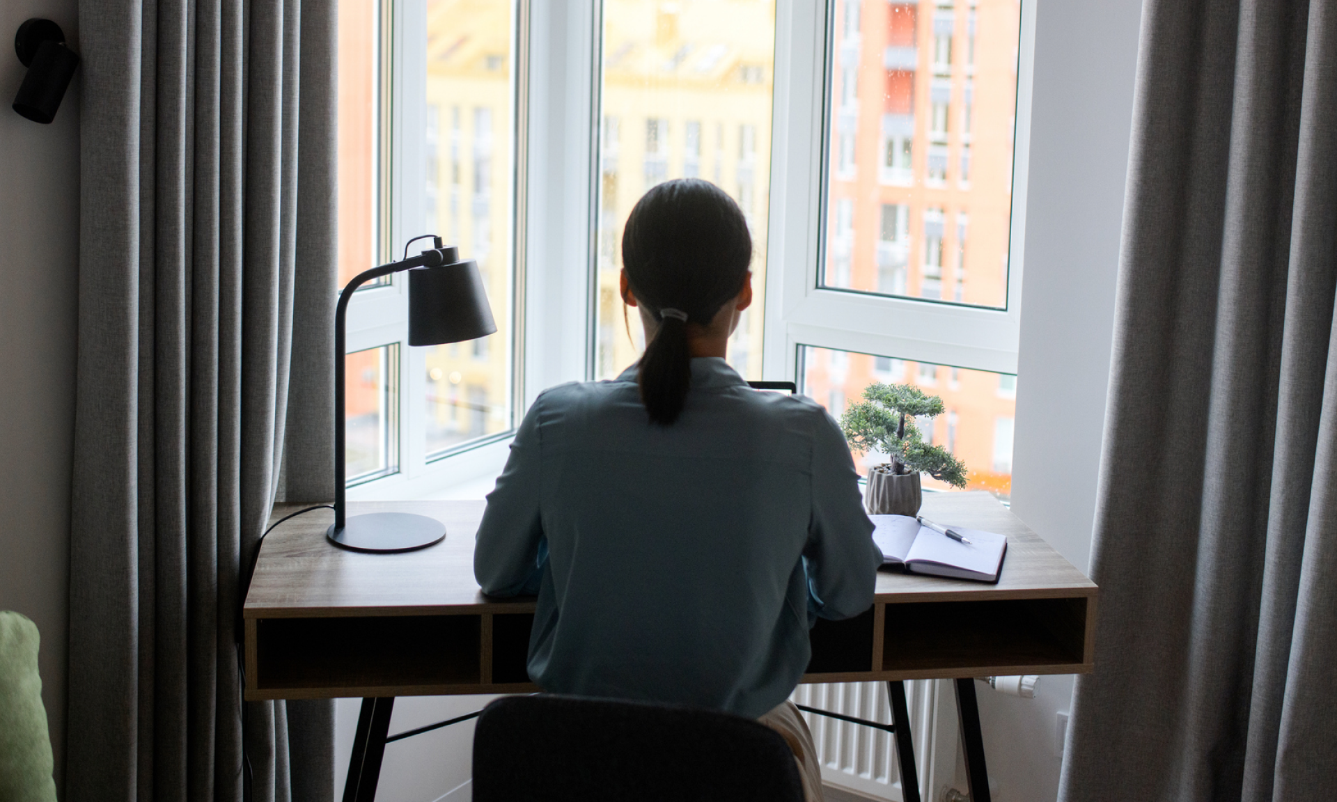 A woman sitting at her desk facing a window