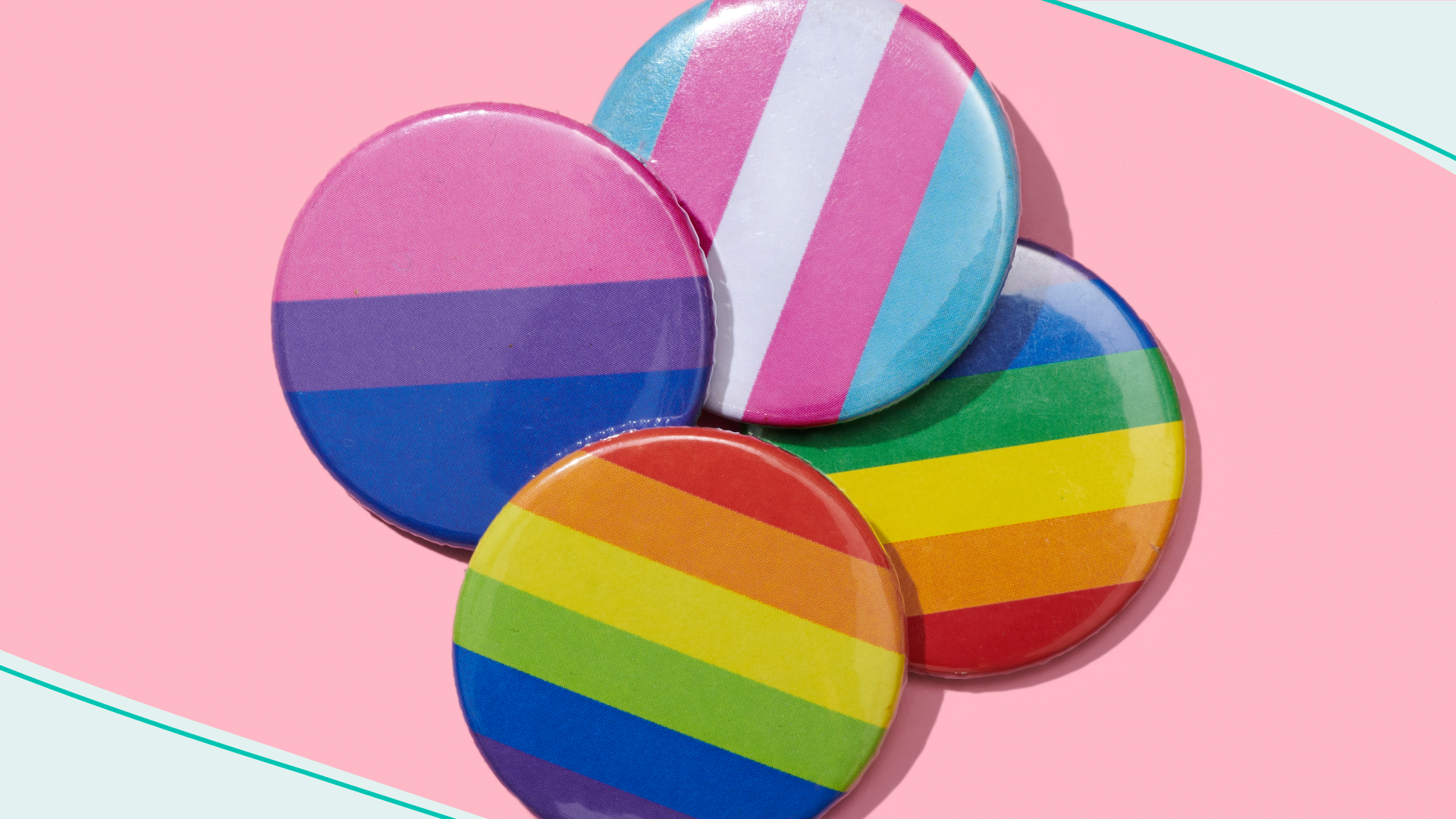 high angle view of some pin buttons patterned with different LGBTIQ flags, such as the gay pride flag, the transgender pride flag or the bisexual pride flag, on a pink background