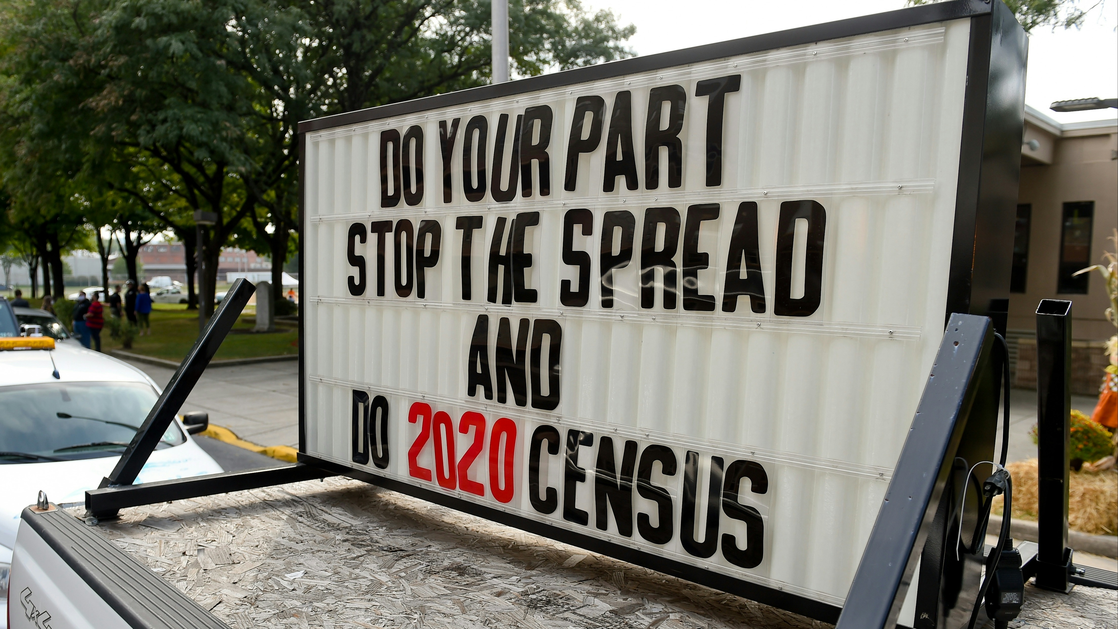 A sign on the back of a truck in the caravan that reads "Do your part, stop the spread and do 2020 Census."