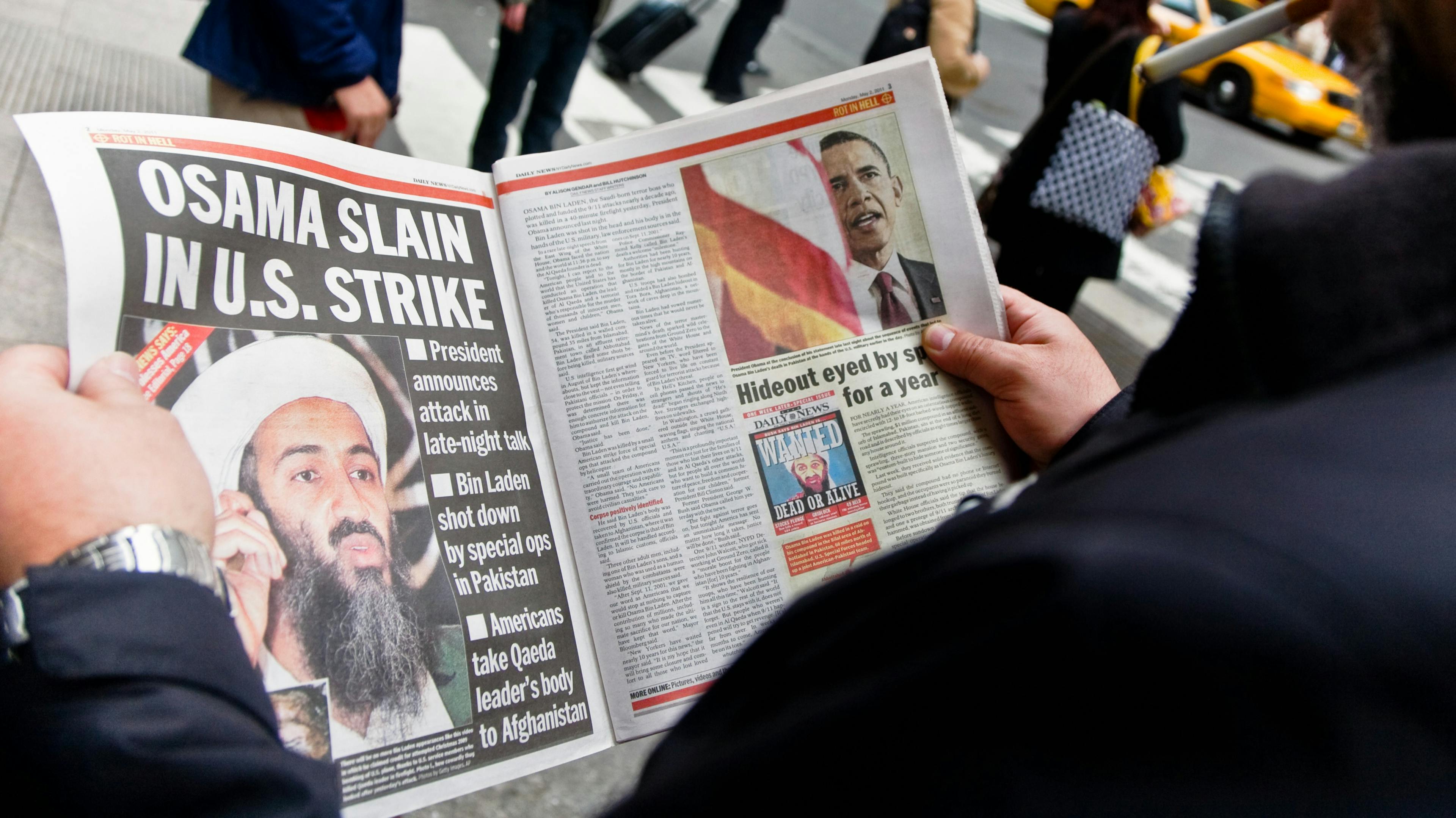 A man reading the newspaper about Osama bin Laden's capture and death. Got Him and Rot in Hell are some of the headlines. 